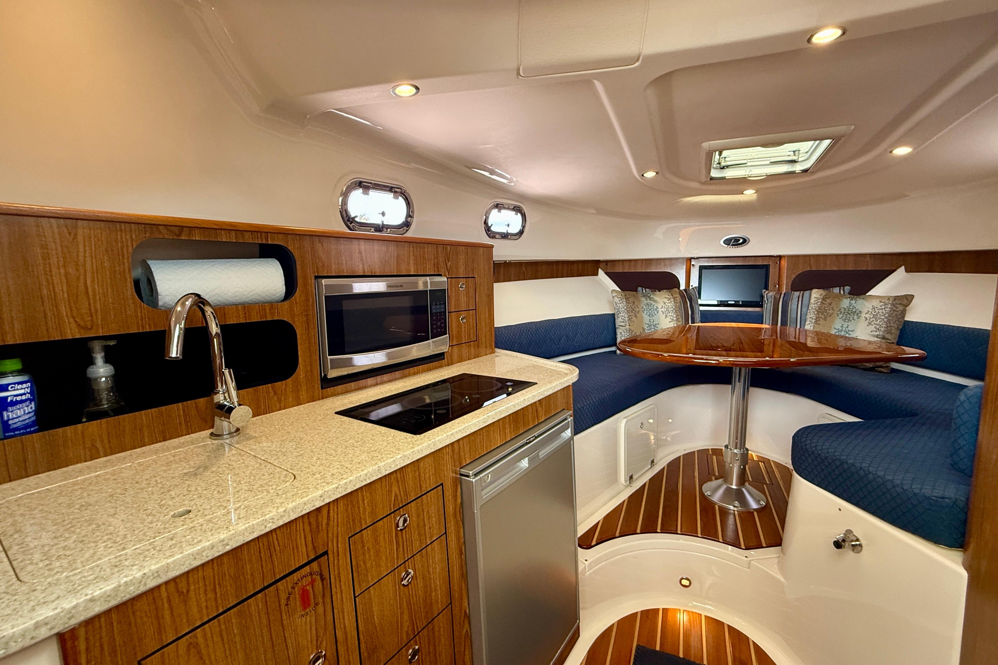 Luxurious interior of a 2012 Pursuit OS 345 Offshore boat with kitchen and seating area.
