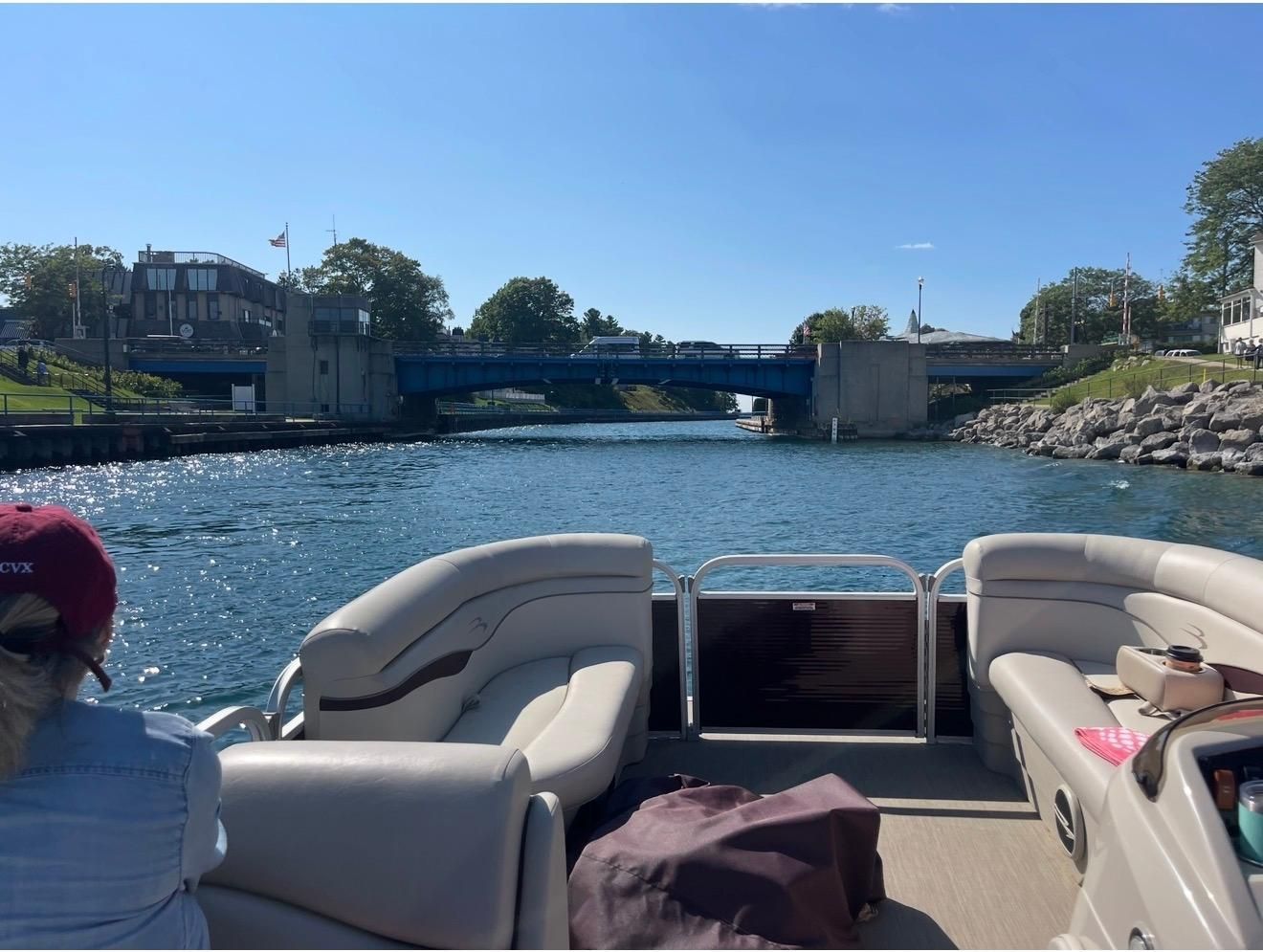 A Bennington 18SL pontoon boat cruising on a river under a blue bridge.