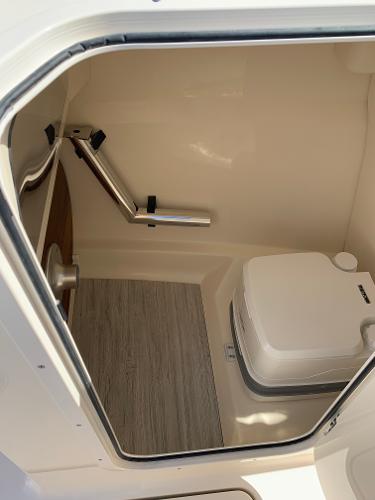 2025 Scout 215 Dorado boat interior with compact toilet and wooden flooring.