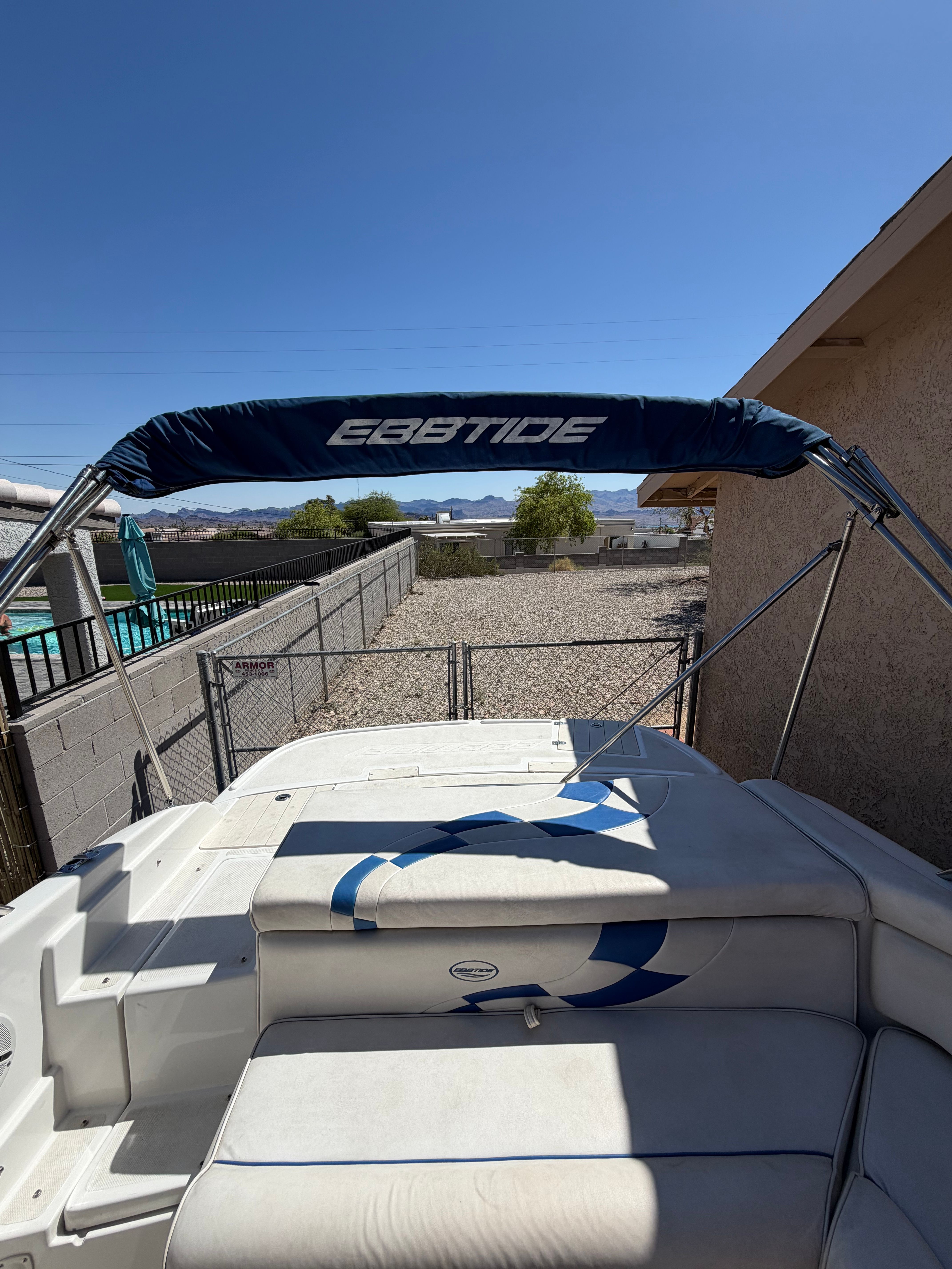 An Ebbtide boat with a sunshade is on dry land next to a building.