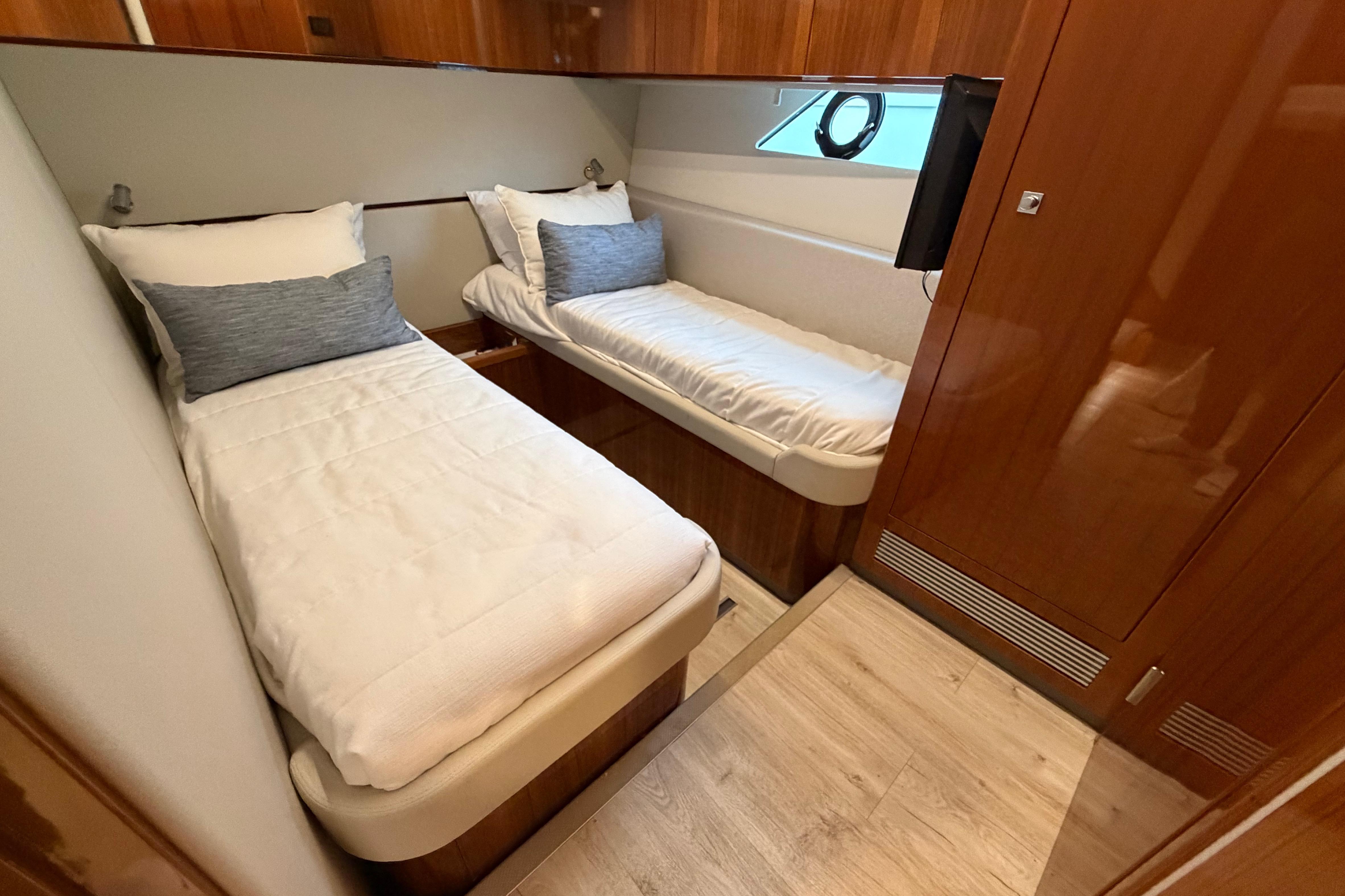 Luxurious twin cabin interior of 2023 Riviera 645 SUV yacht with wooden finishes.