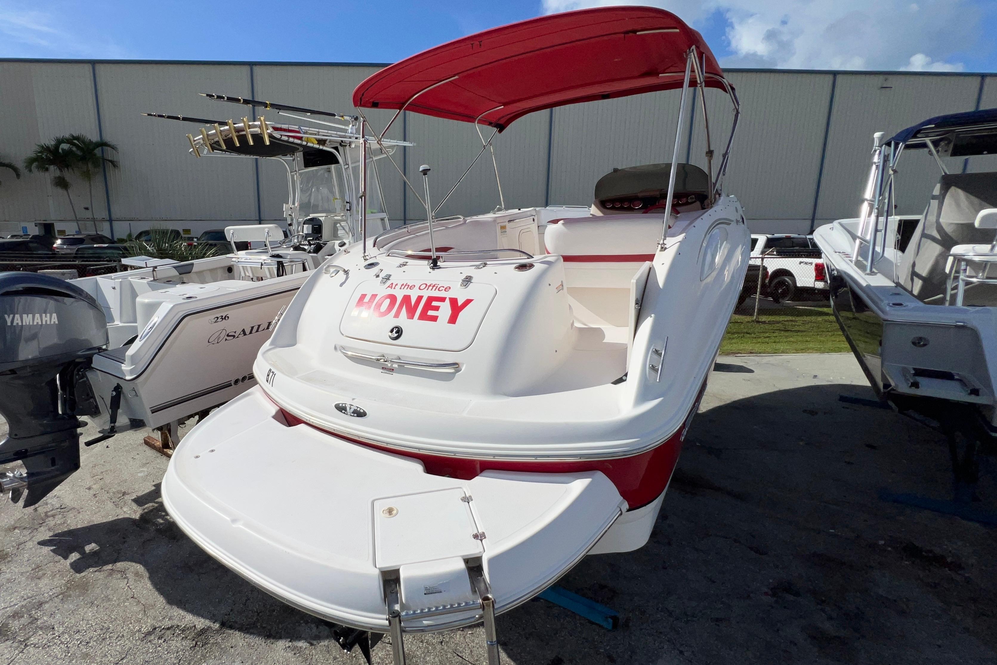 2002 Chaparral 232 Sunesta boat with red canopy, docked outdoors.