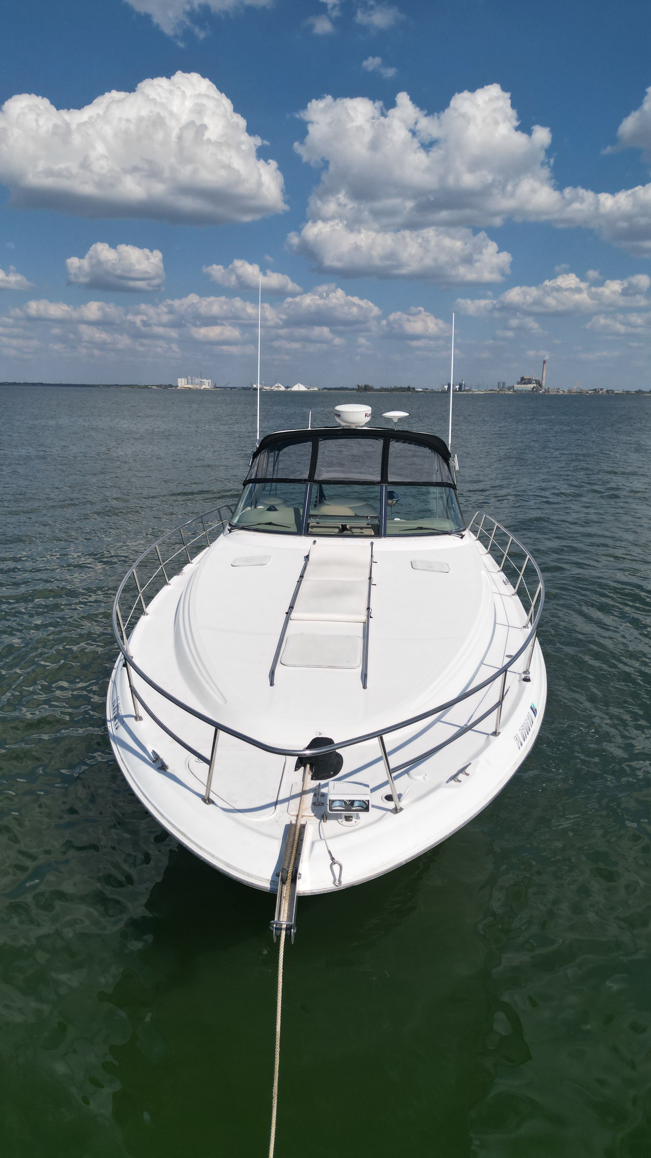 A white motorboat on calm water under a blue sky with clouds.