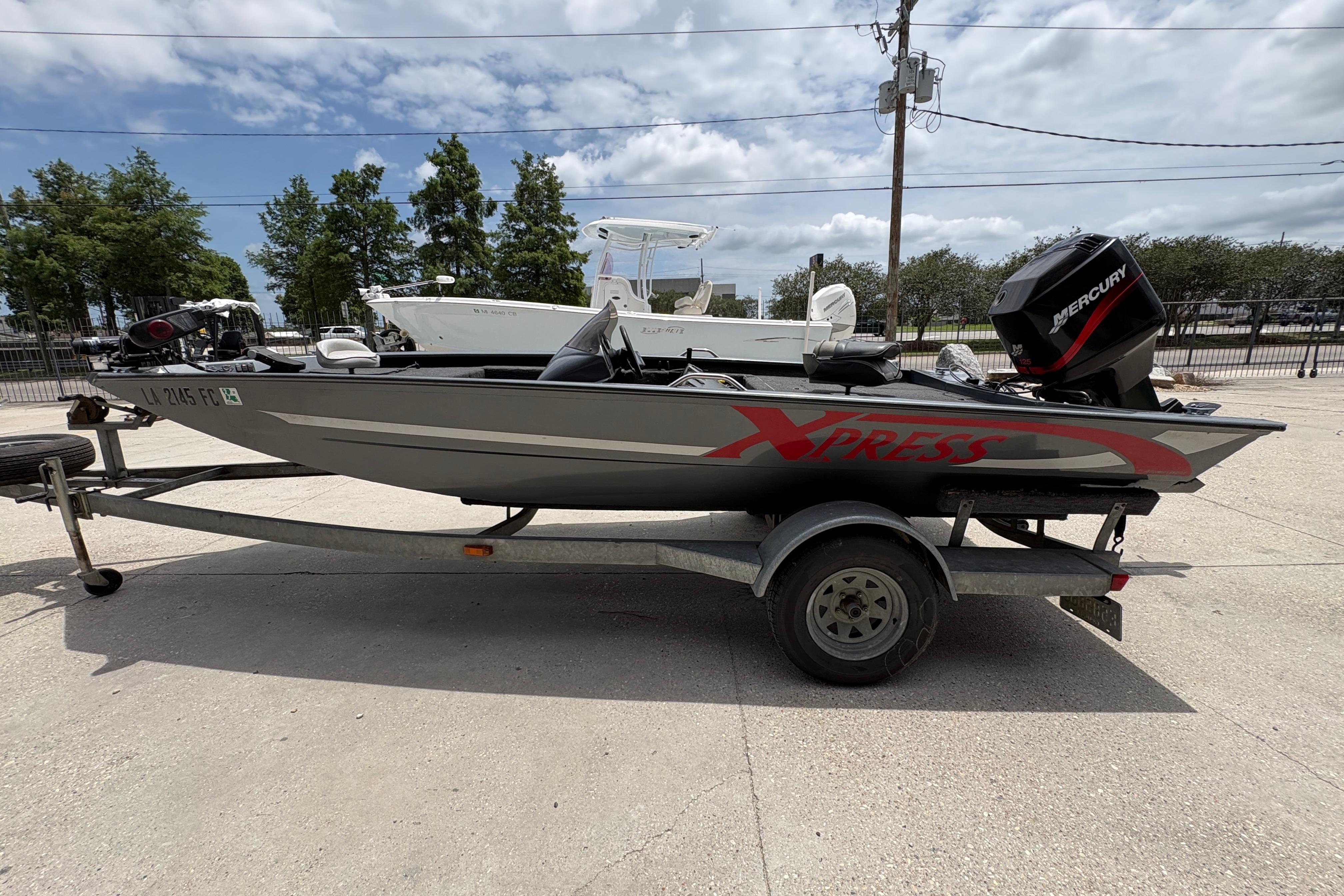 2000 Xpress X18 boat on trailer with Mercury engine, parked outdoors.