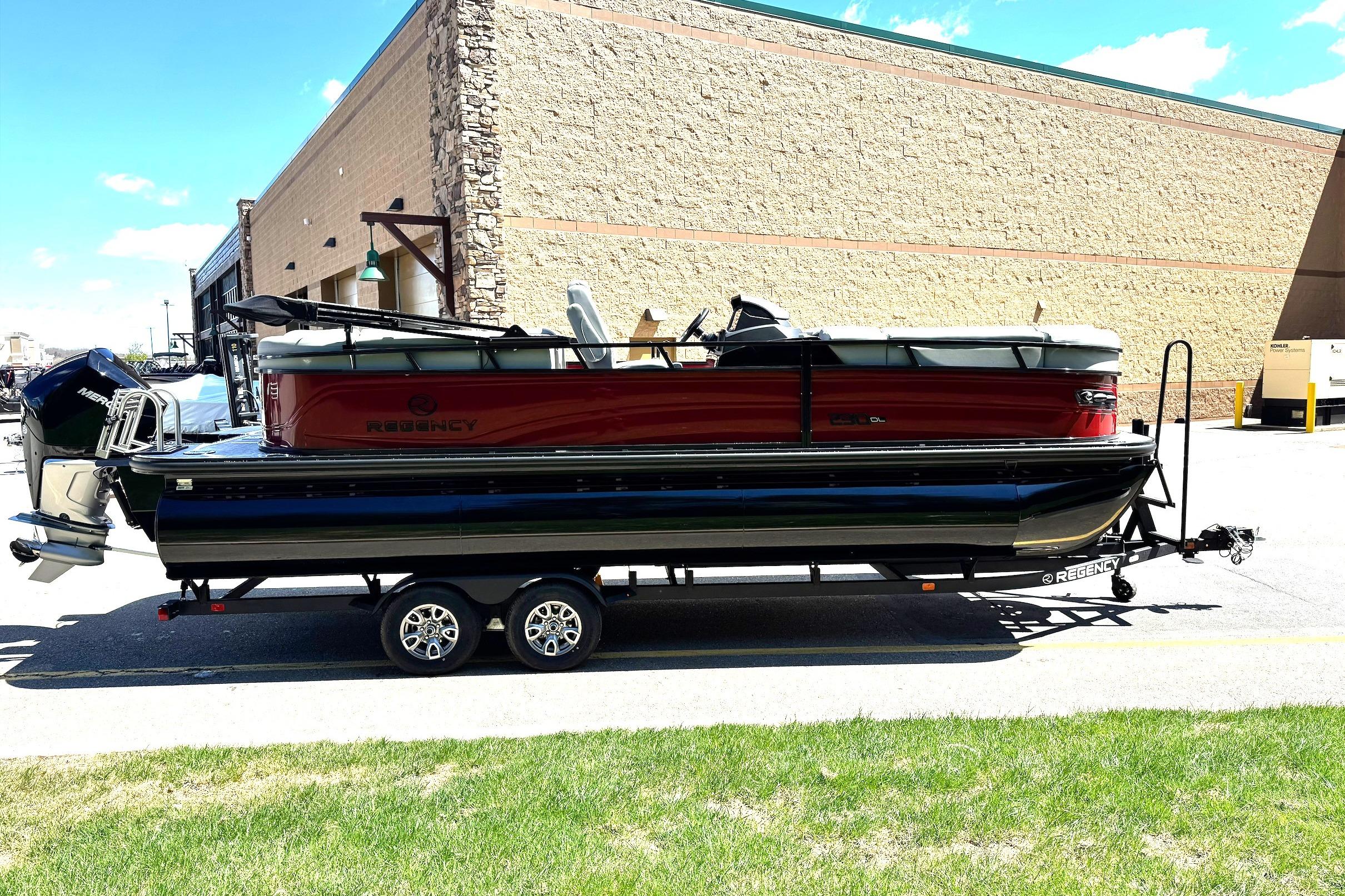 2026 Regency 230 DL pontoon boat on trailer, parked outdoors near a building.