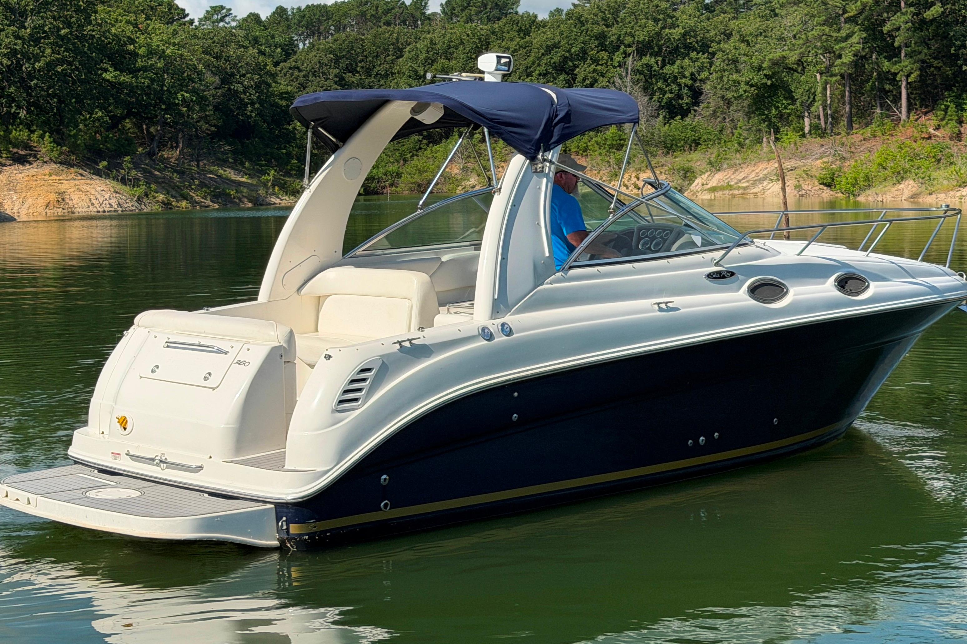 2004 Sea Ray Sundancer 260 boat on a calm lake with lush green surroundings.