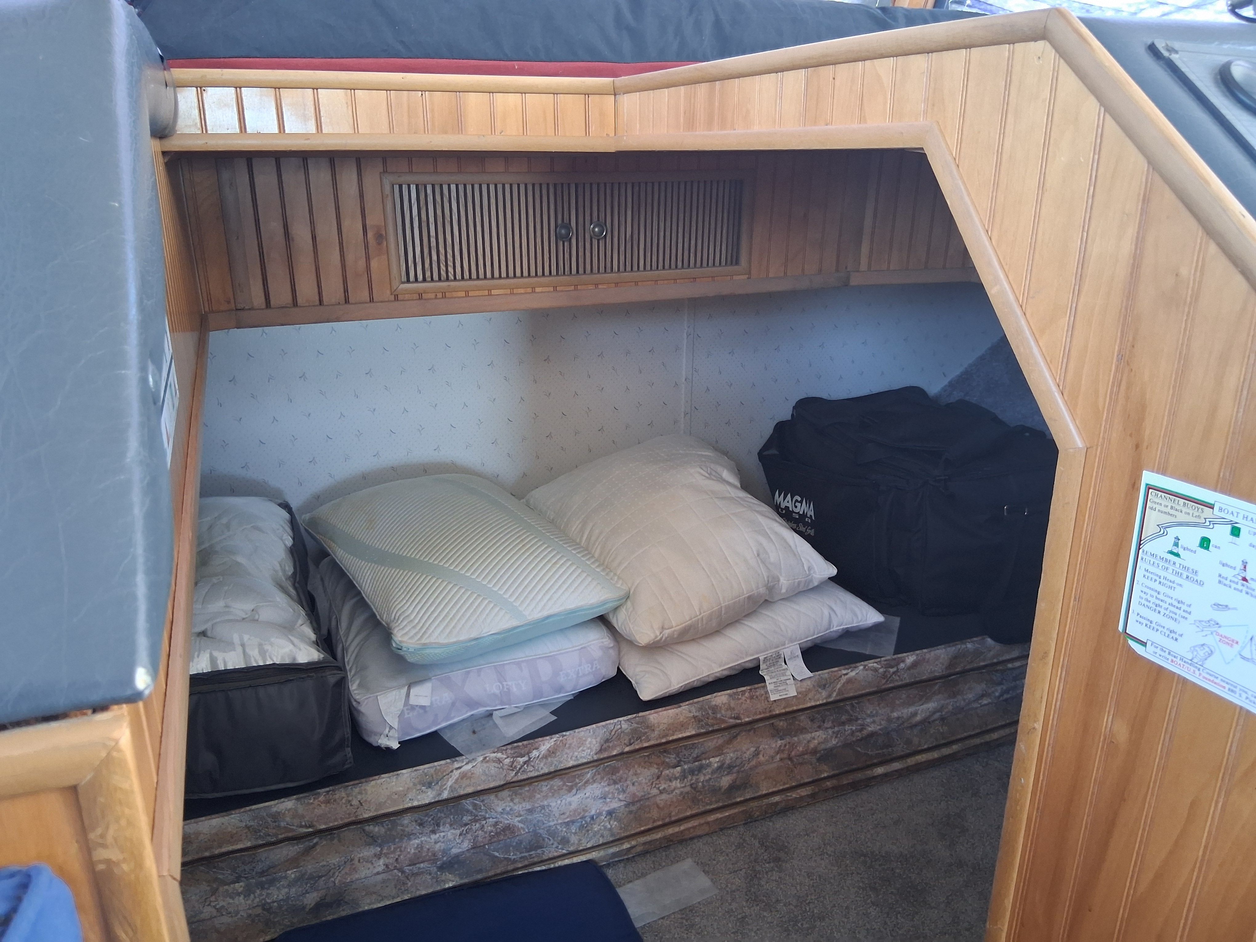 A cozy sleeping area with pillows and blankets inside a boat.