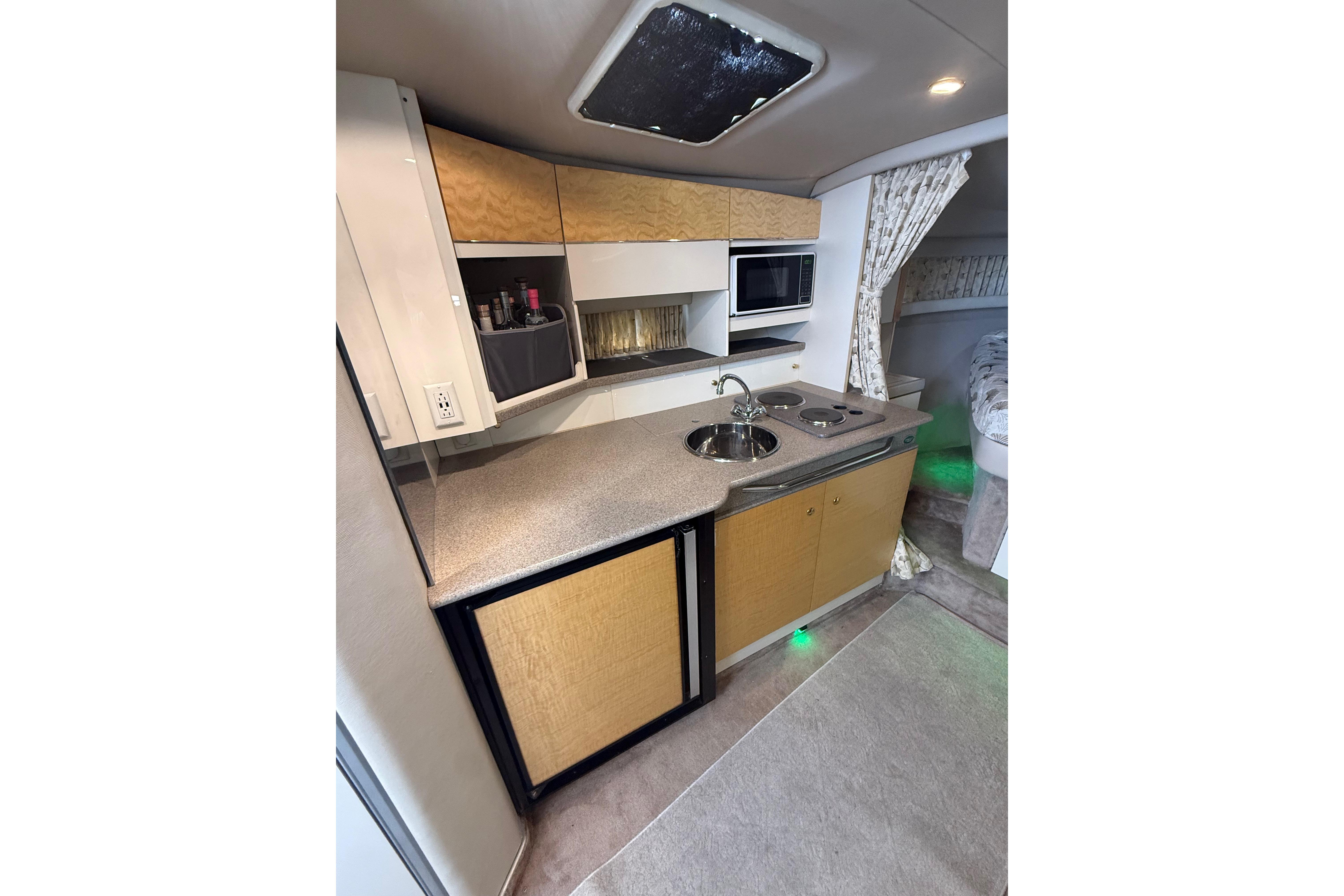 1999 Formula 34 Performance Cruiser kitchen with sink, stove, microwave, and storage cabinets.