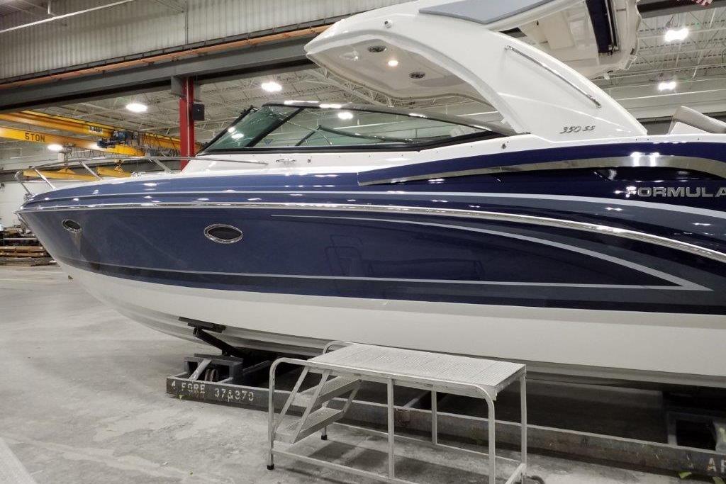 2021 Formula 350 Sun Sport boat in a showroom, showcasing sleek blue and white design.