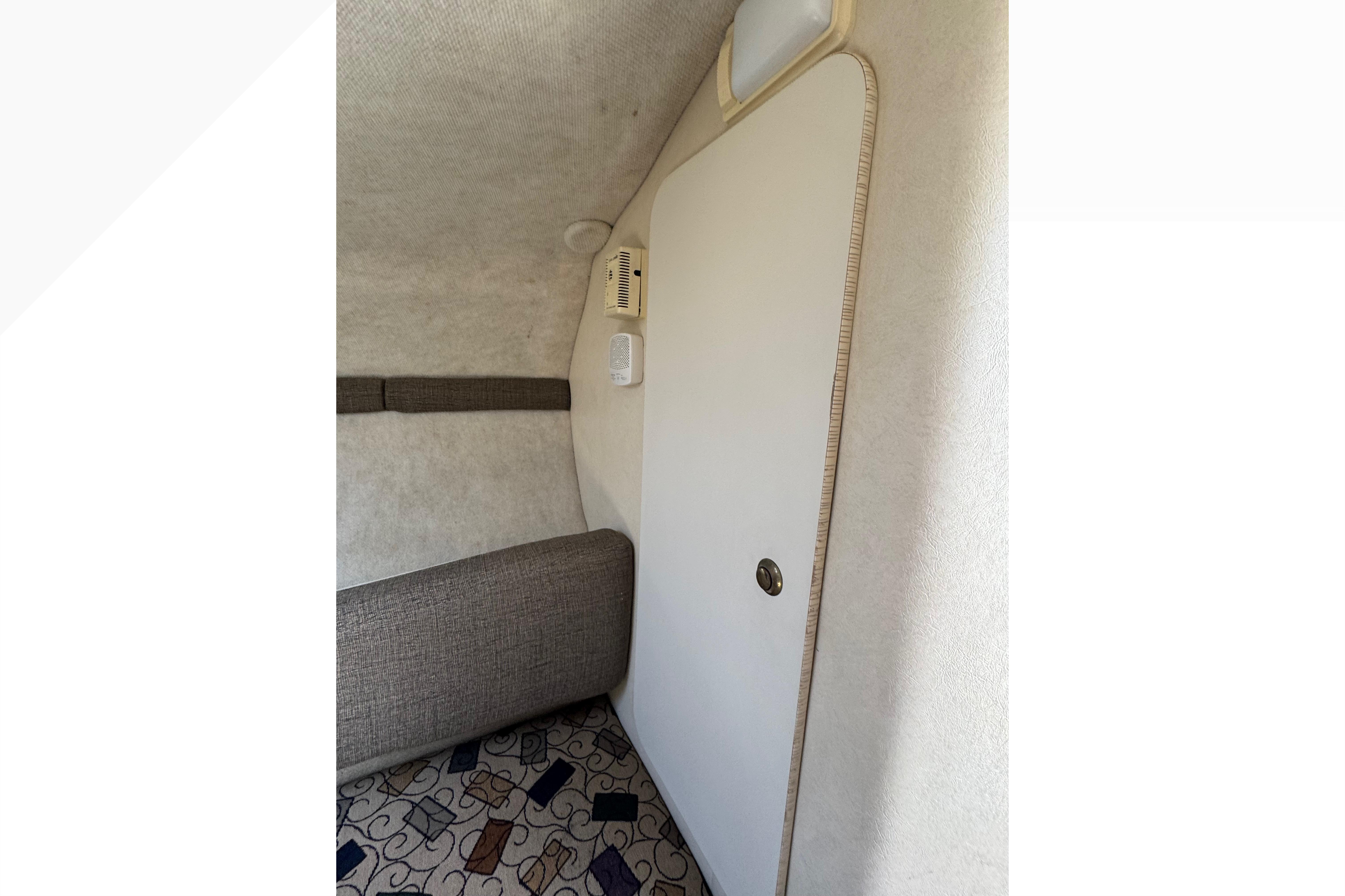 Interior cabin of 2001 Sea Ray 245 Weekender with cushioned seating and patterned carpet.
