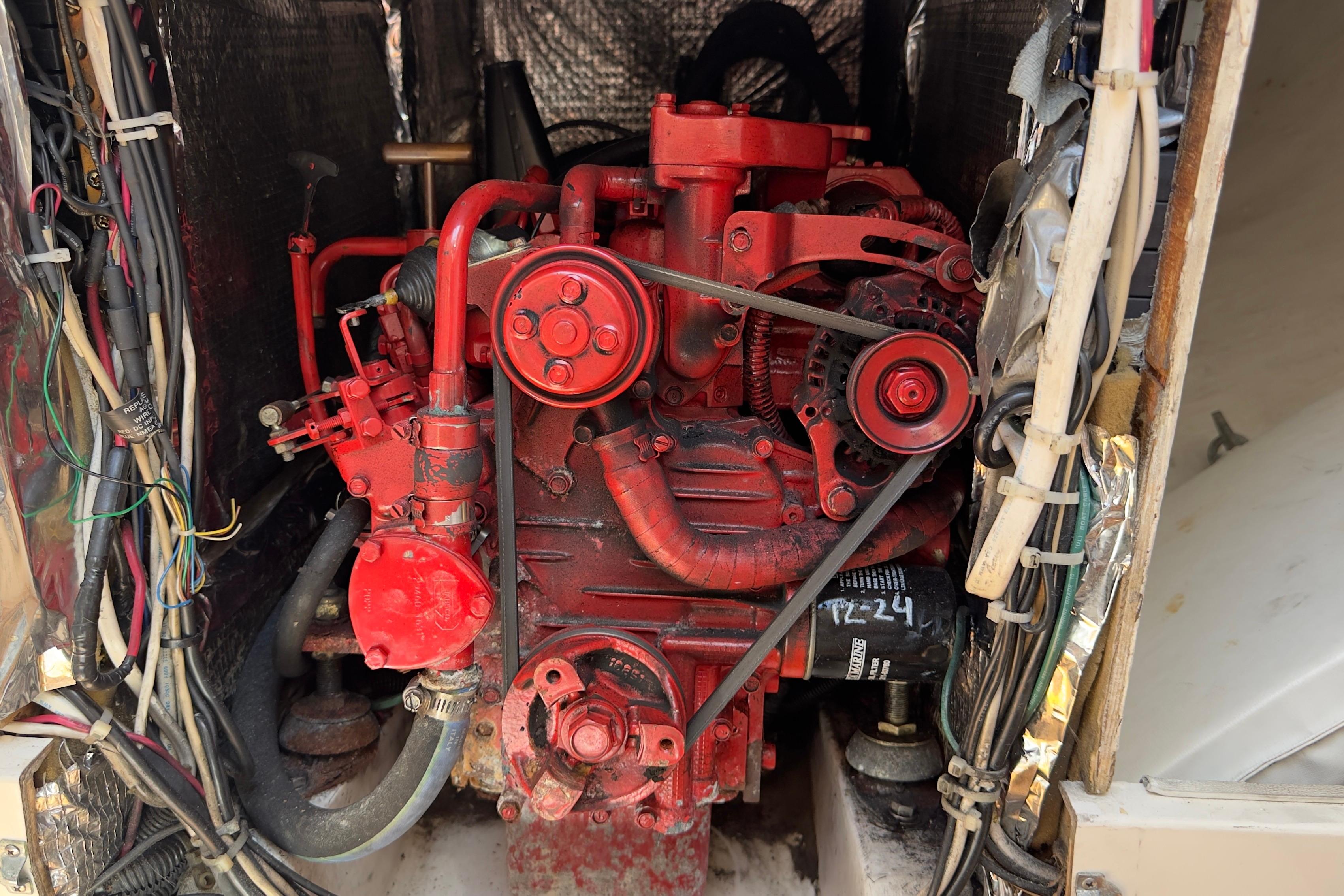 Red engine inside a 1994 J Boats J/92 sailboat, surrounded by wiring.