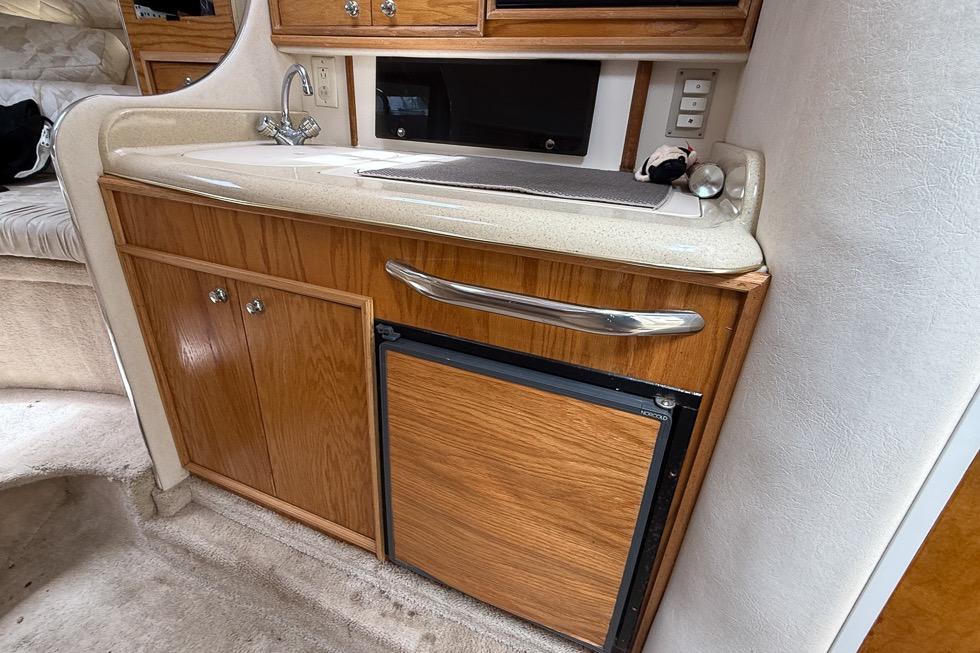 1999 Sea Ray 290 Sundancer cabin kitchenette with sink and mini fridge.