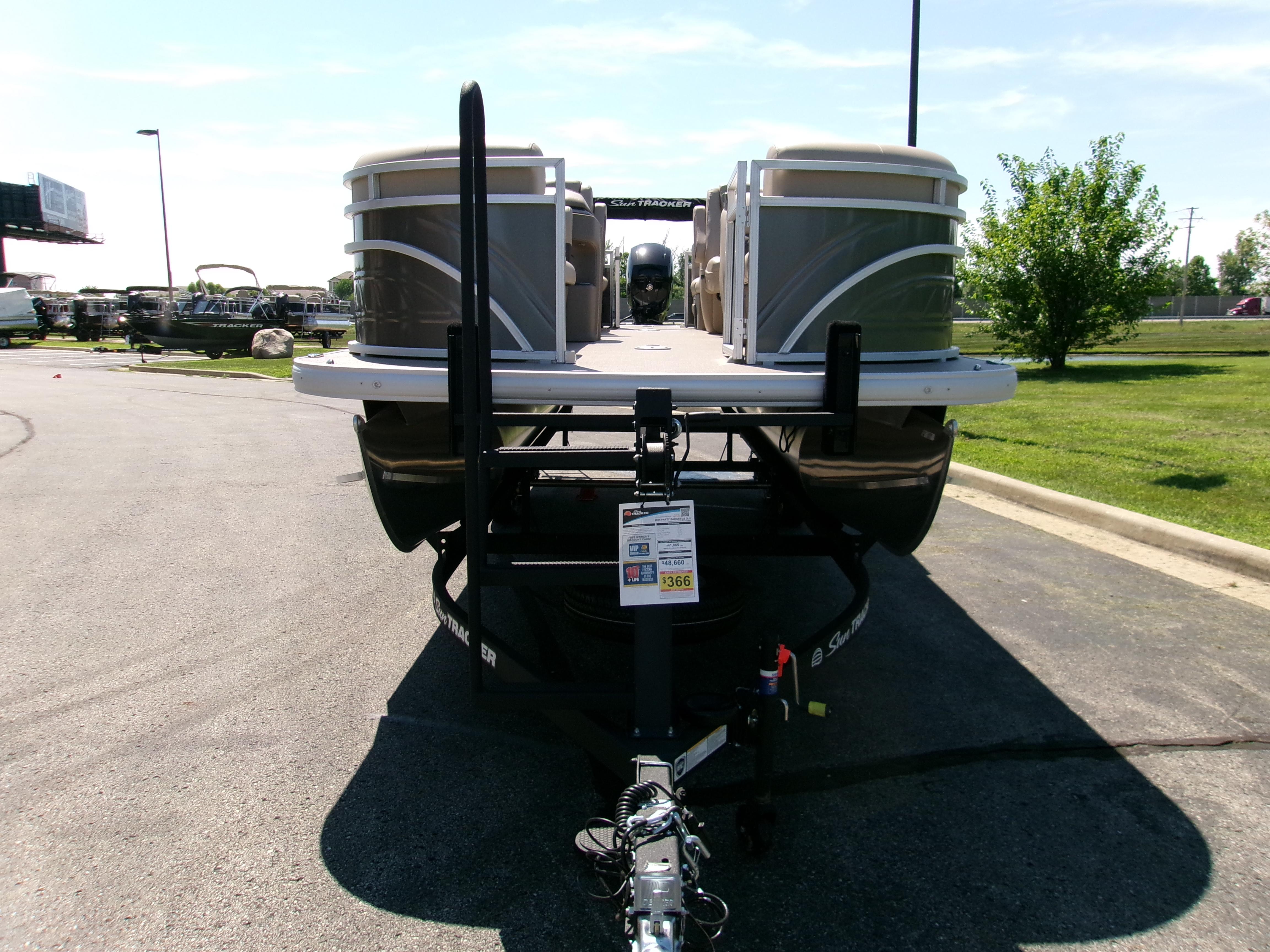 2025 Sun Tracker Party Barge 22 DLX pontoon boat on trailer in parking lot.