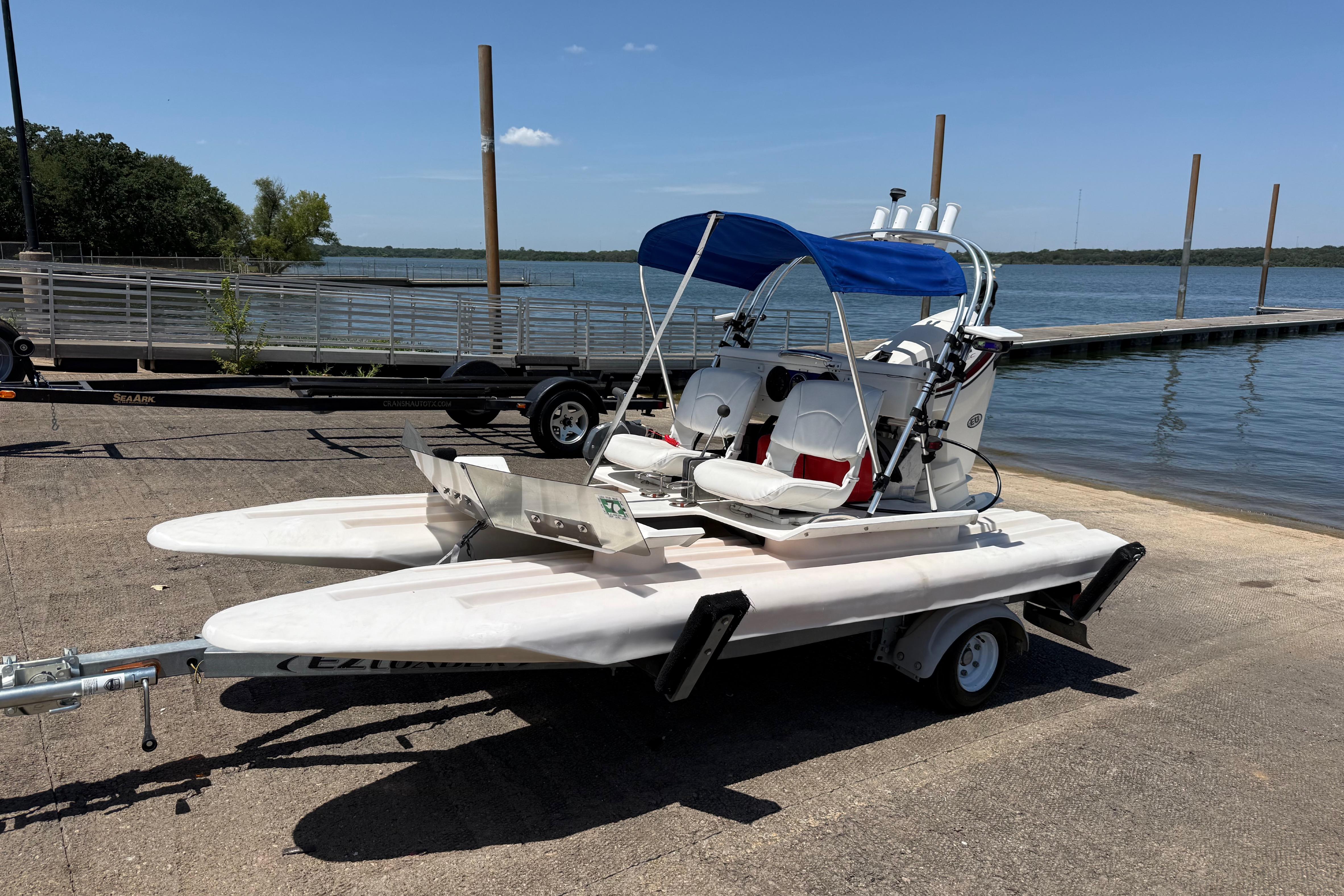 2016 CraigCat E2 Elite catamaran on trailer by a lakeside dock under clear blue sky.