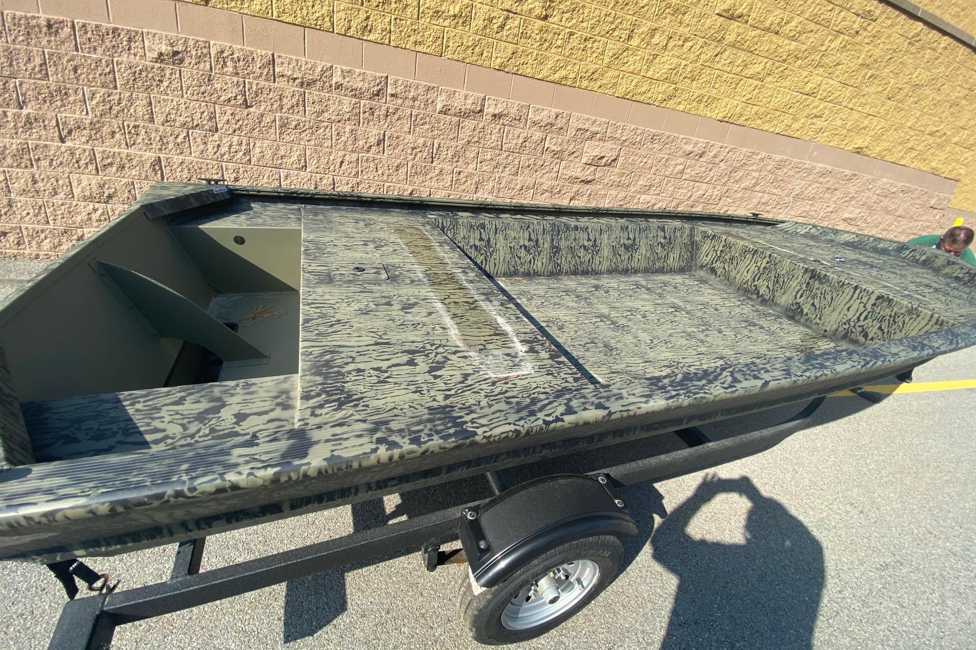 2026 Tracker Grizzly 1648 Utility boat on trailer, camouflage pattern, parked outdoors.