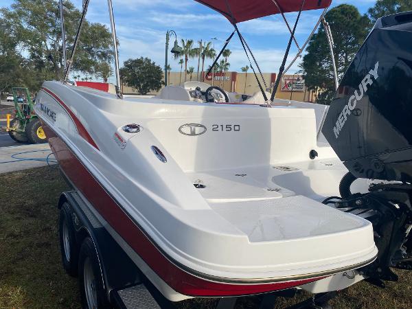 2022 Tahoe 2150 boat with Mercury engine, red and white design, parked outdoors.