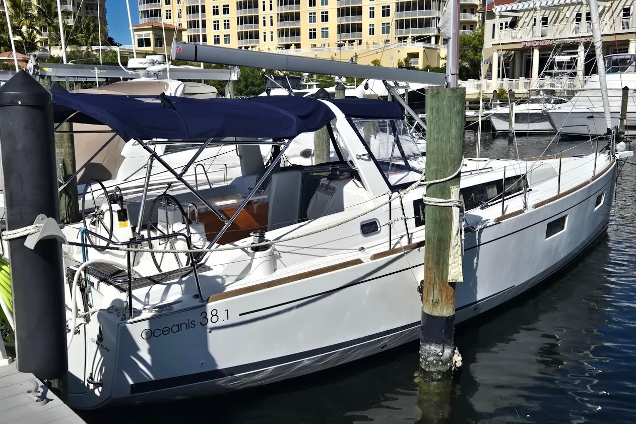 2023 Beneteau Oceanis 38.1 yacht docked at marina, featuring sleek design and blue canopy.