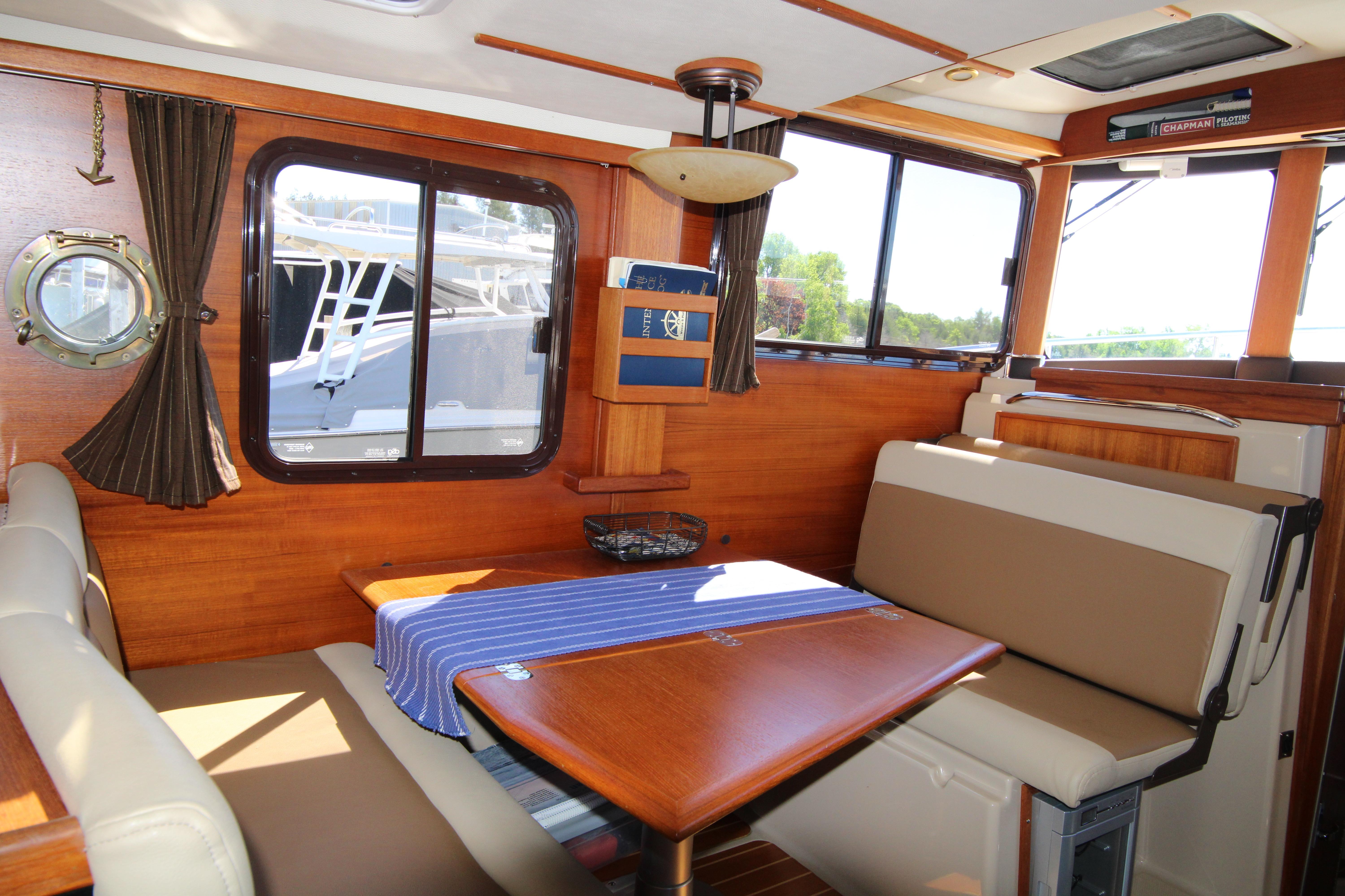 Interior of 2013 Ranger Tugs R-31 CB with wooden dining area and blue tablecloth.