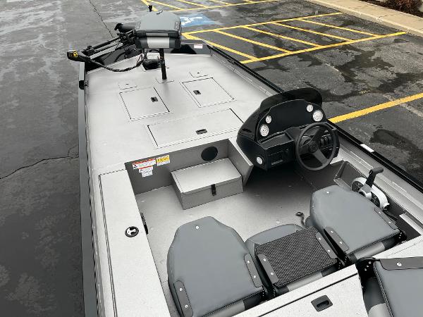 2024 Lowe Legacy boat interior with steering console and seating in a parking lot.