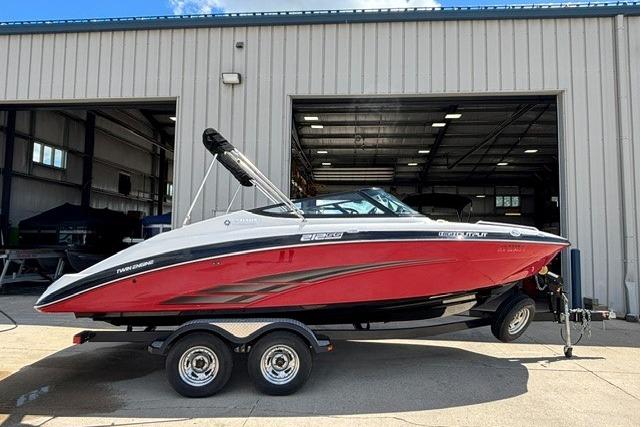 2014 Yamaha Boats 212X in red, parked on a trailer outside a warehouse.
