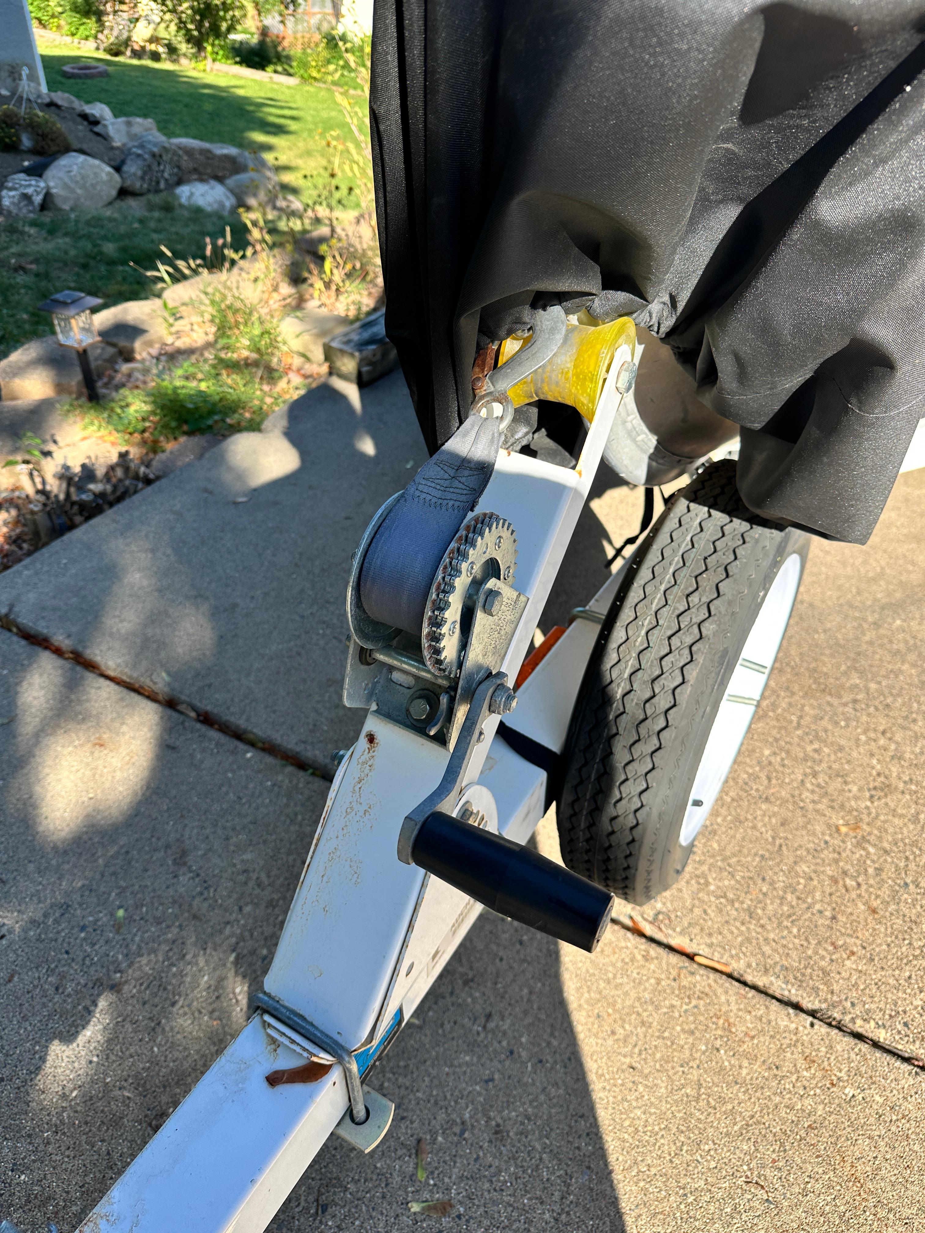 1960 Lund H boat trailer with winch and wheel on a sunny driveway.