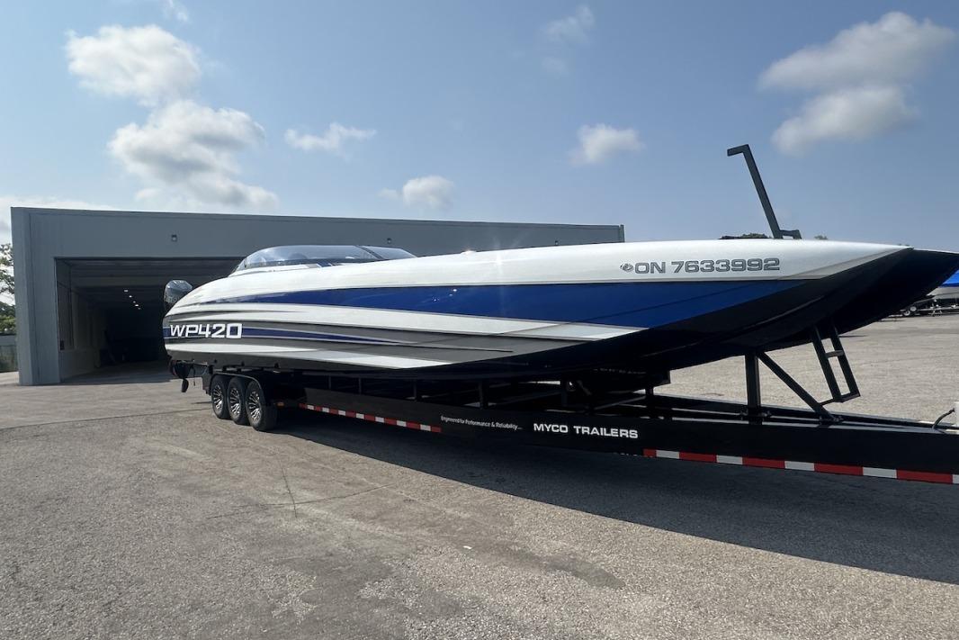 2018 Wright Performance 420 boat on trailer outside a garage under a clear sky.