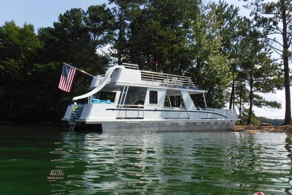 2008 Destination Yachts 45X14 houseboat on a serene lake, surrounded by trees.