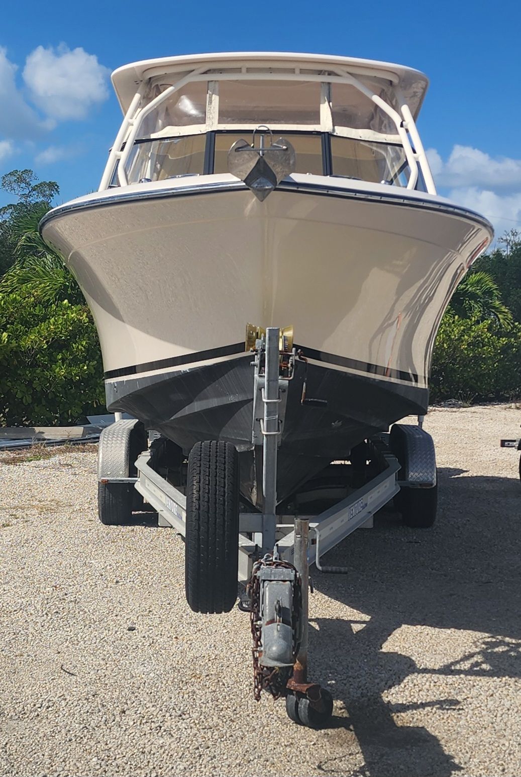 A 2015 Grady-White Freedom 275 boat on a trailer, surrounded by trees.