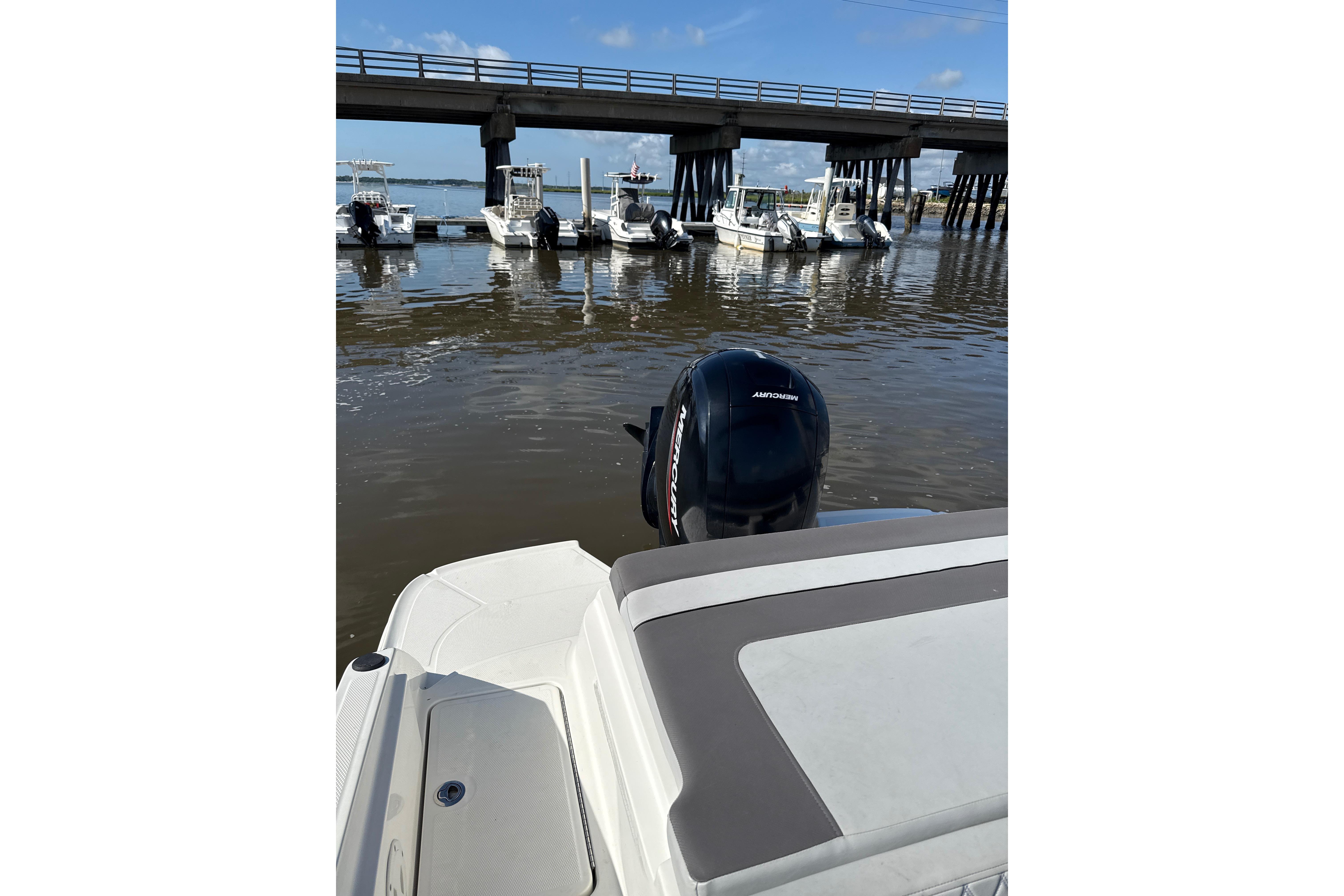 2023 Bayliner VR6 Bowrider OB on water near docked boats and bridge.