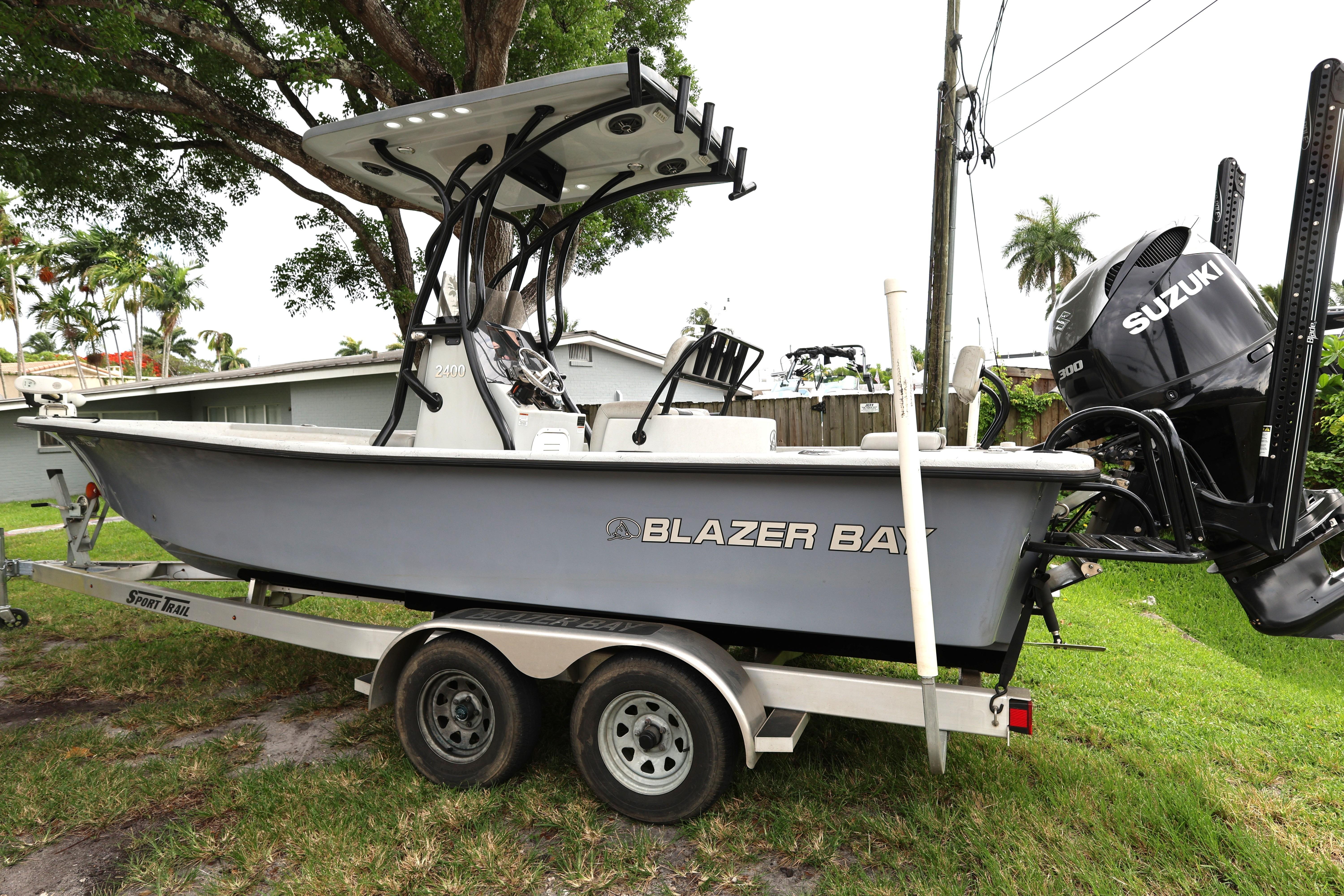2021 Blazer Bay 2400 boat on trailer with Suzuki engine, parked outdoors.