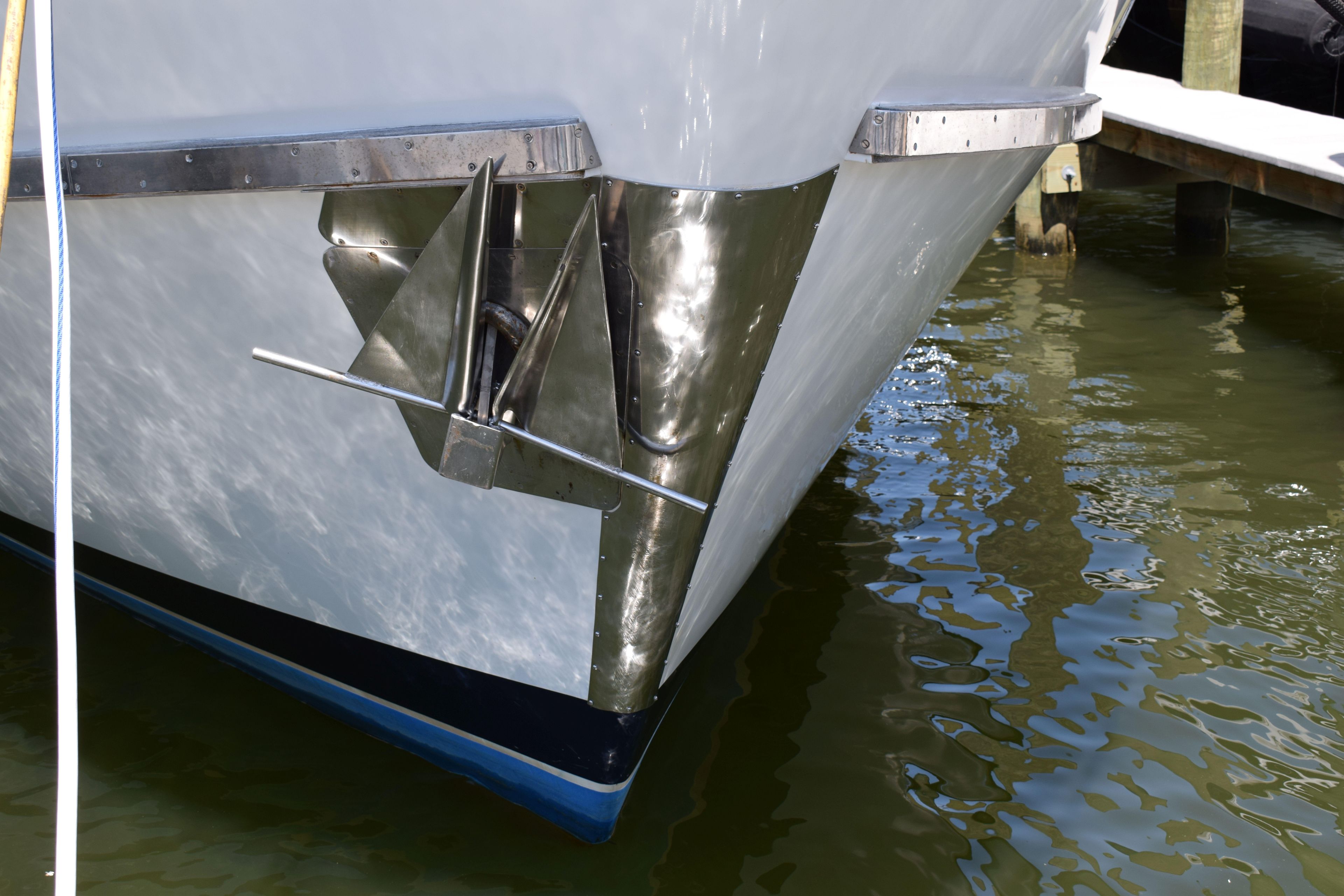 Bow of 1980 Cheoy Lee 52 Motorsailer with anchor, docked in calm water.
