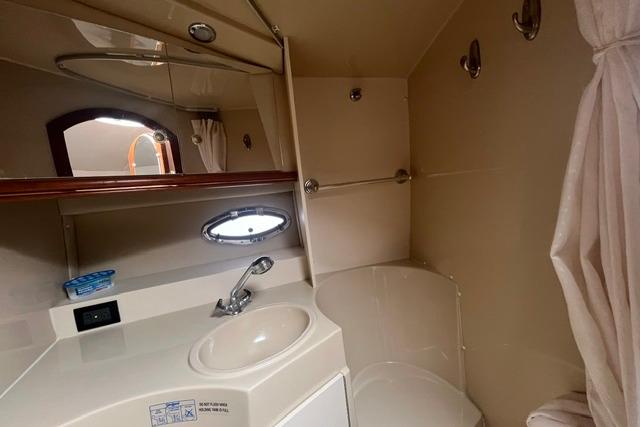 2004 Cruisers Yachts 3372 Express bathroom with sink, mirror, and shower curtain.