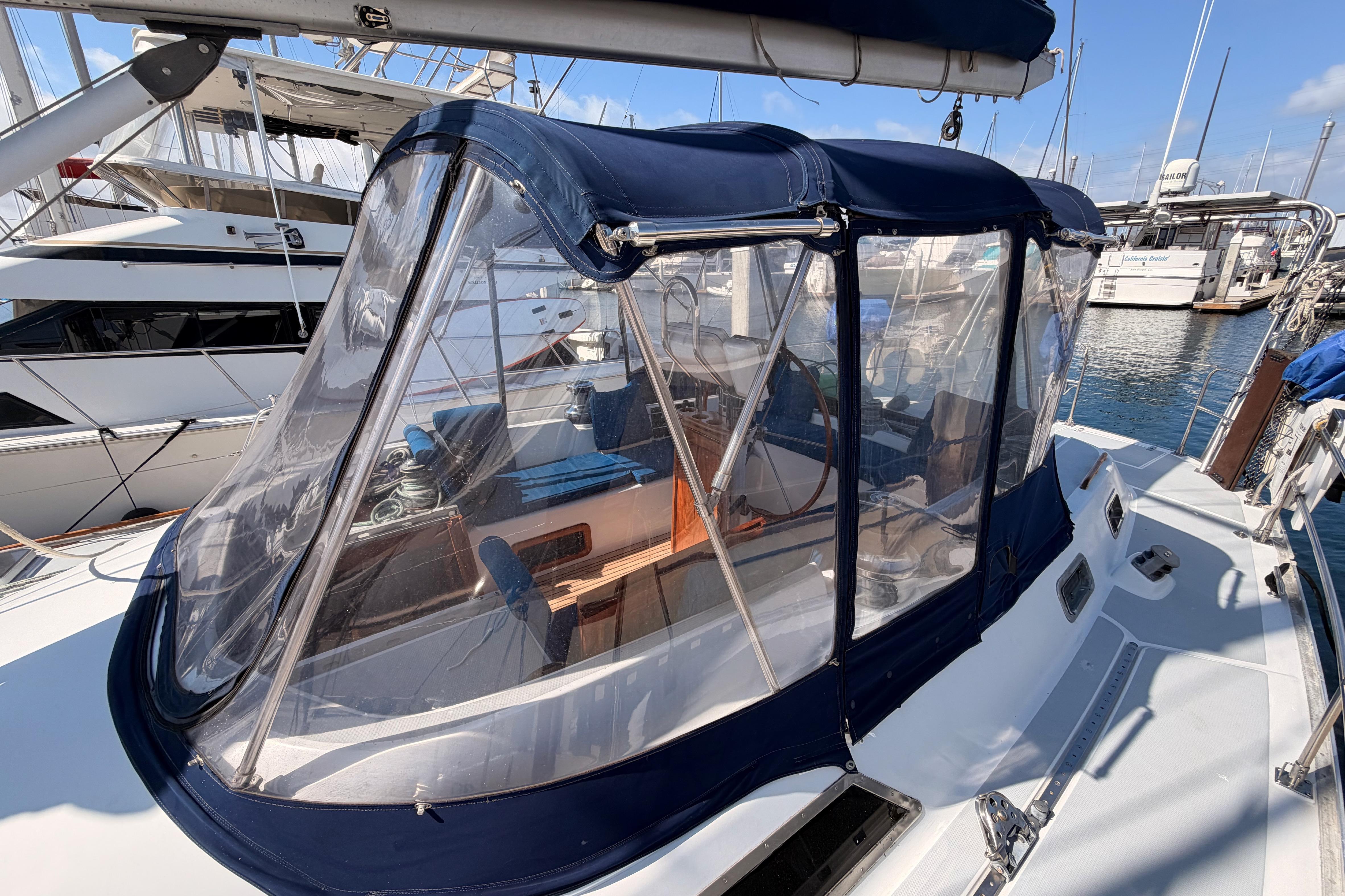 1991 Hylas 51 sailboat with blue canopy docked at marina.
