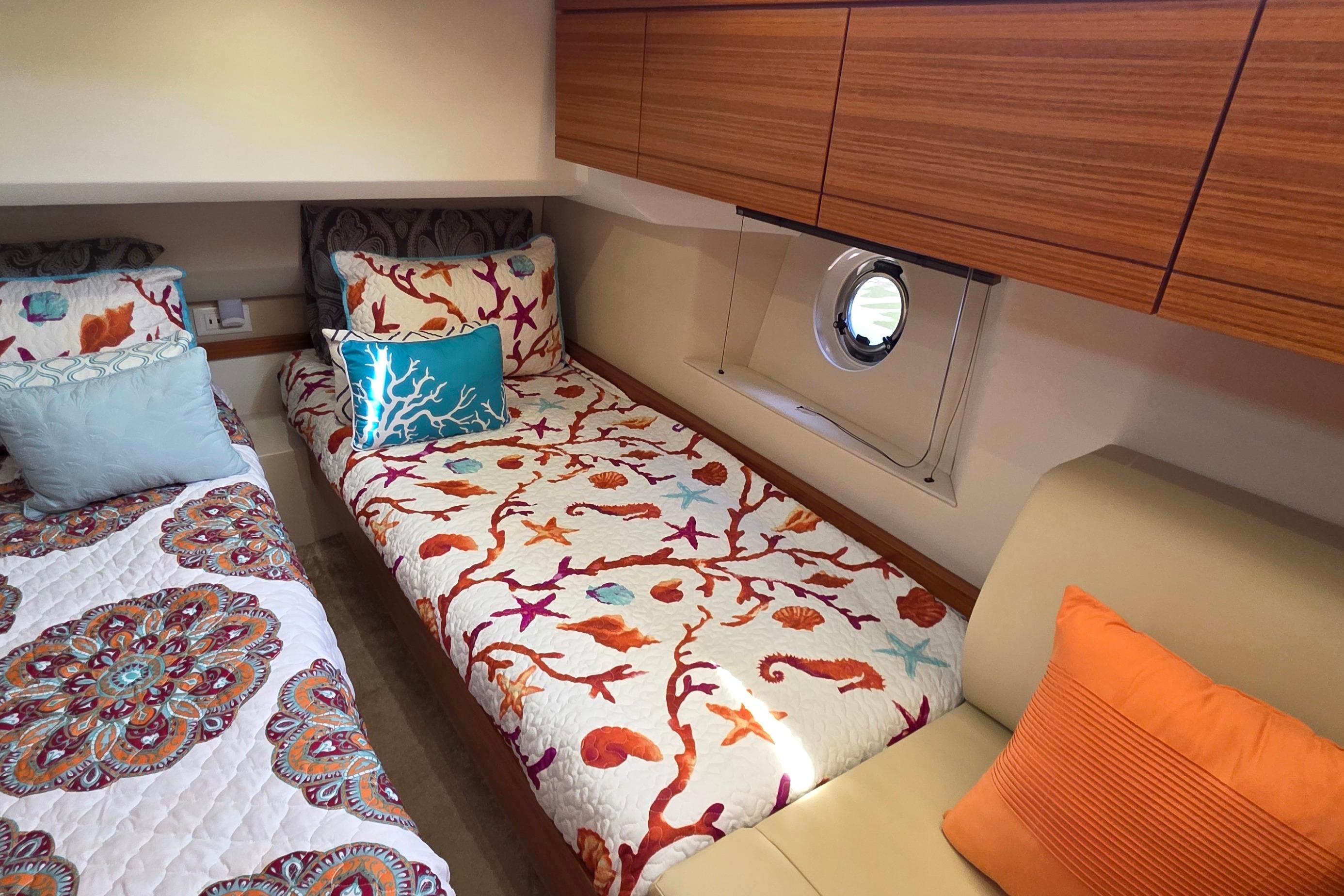 Cozy cabin interior of 2023 Greenline 40 yacht with vibrant bedding and wooden cabinets.