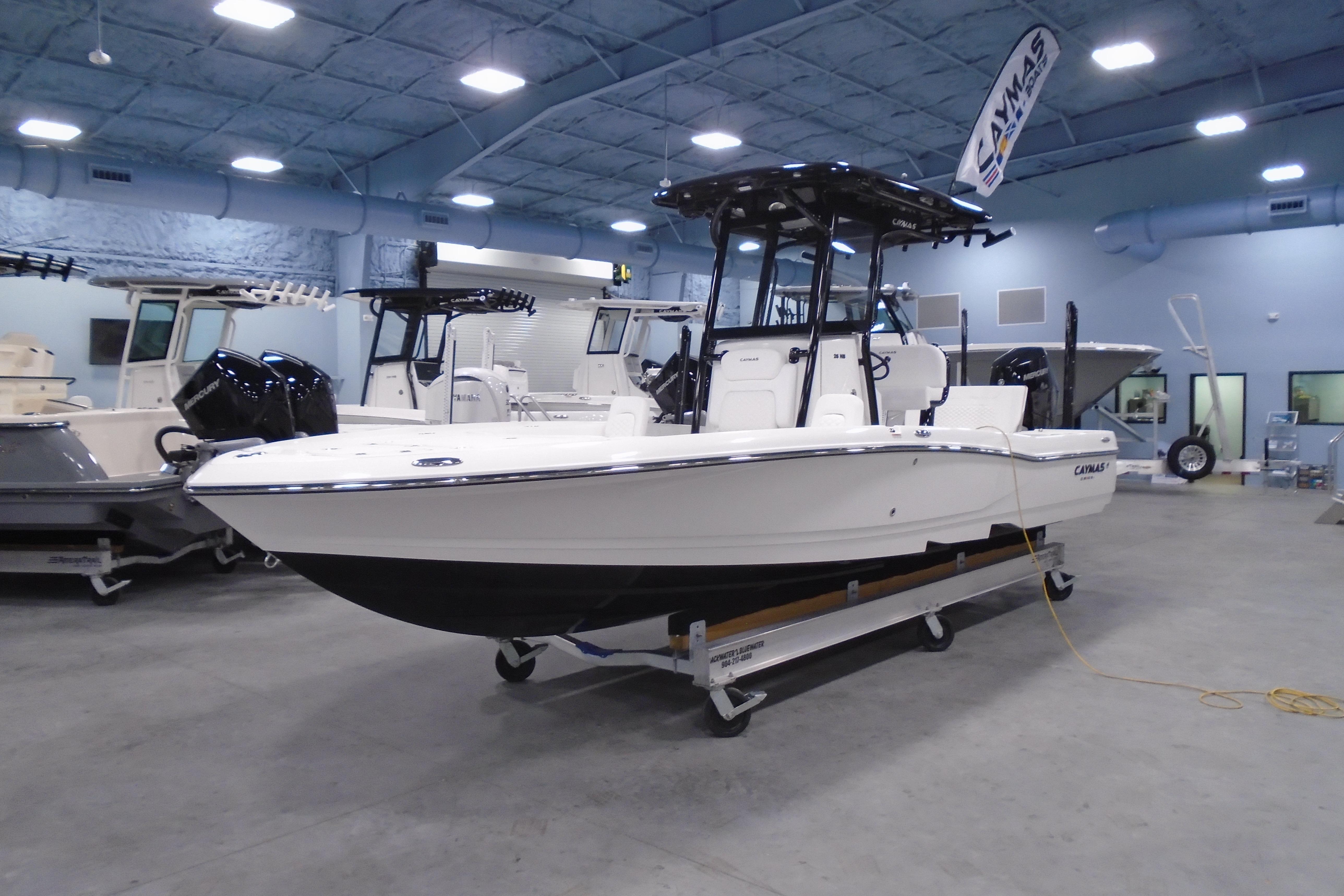 2026 Caymas 26 HB boat displayed indoors, featuring sleek design and dual engines.