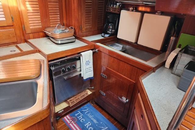 1984 Bristol 45.5 Center Cockpit yacht kitchen with wooden cabinetry and modern appliances.