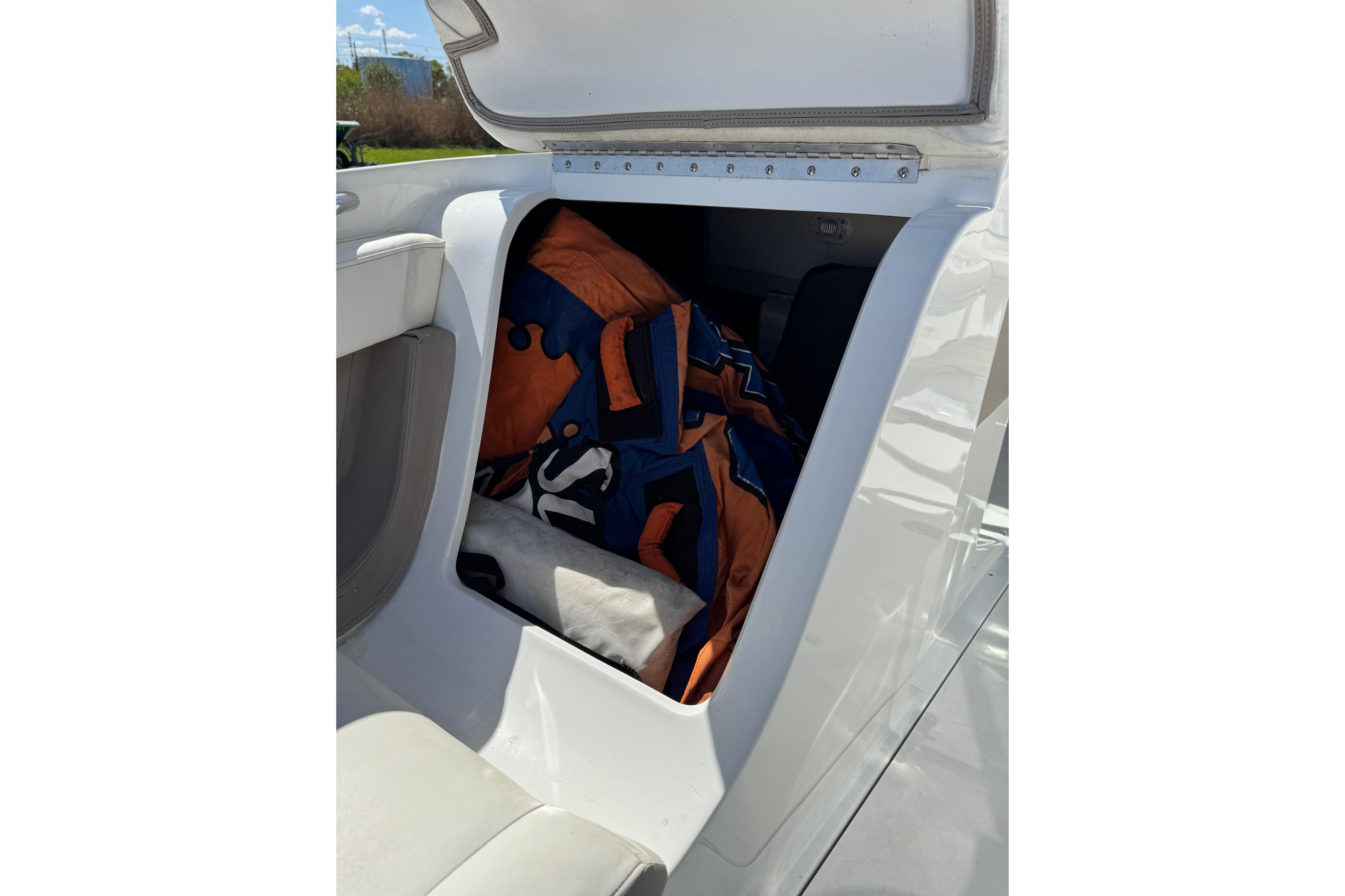 Open storage compartment in 2005 Cobalt 240 boat with life jackets inside.