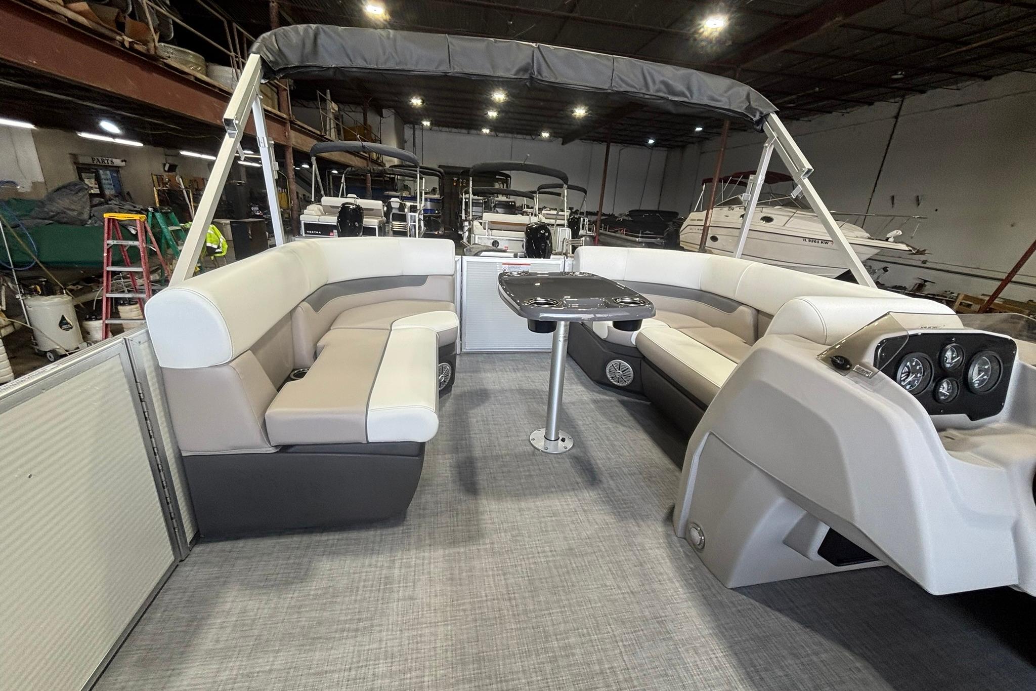 2025 Princecraft Vectra 21 RL pontoon boat interior with seating and table in a showroom.