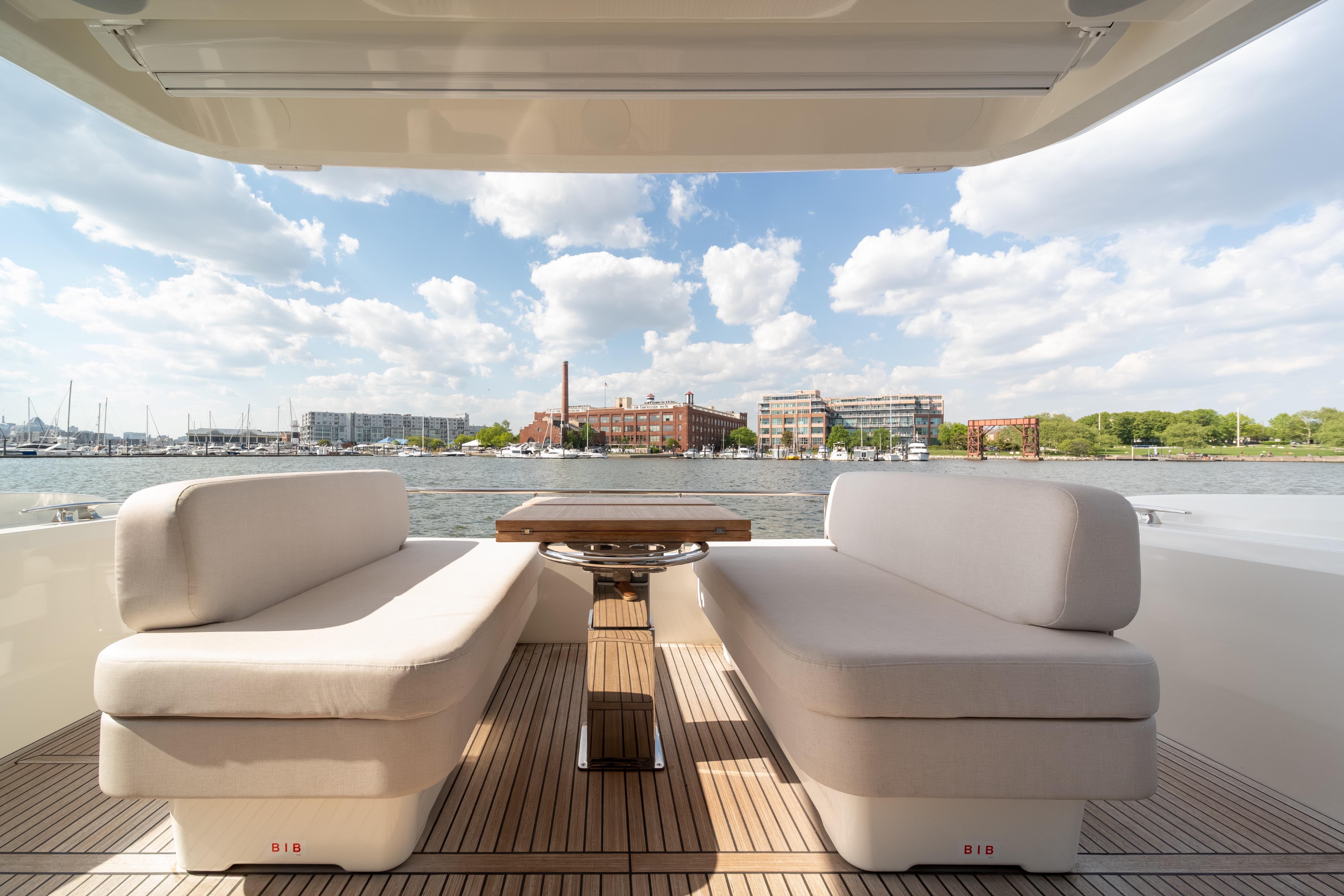 Luxurious Prestige F4.9 yacht deck with elegant seating, overlooking a scenic waterfront view.