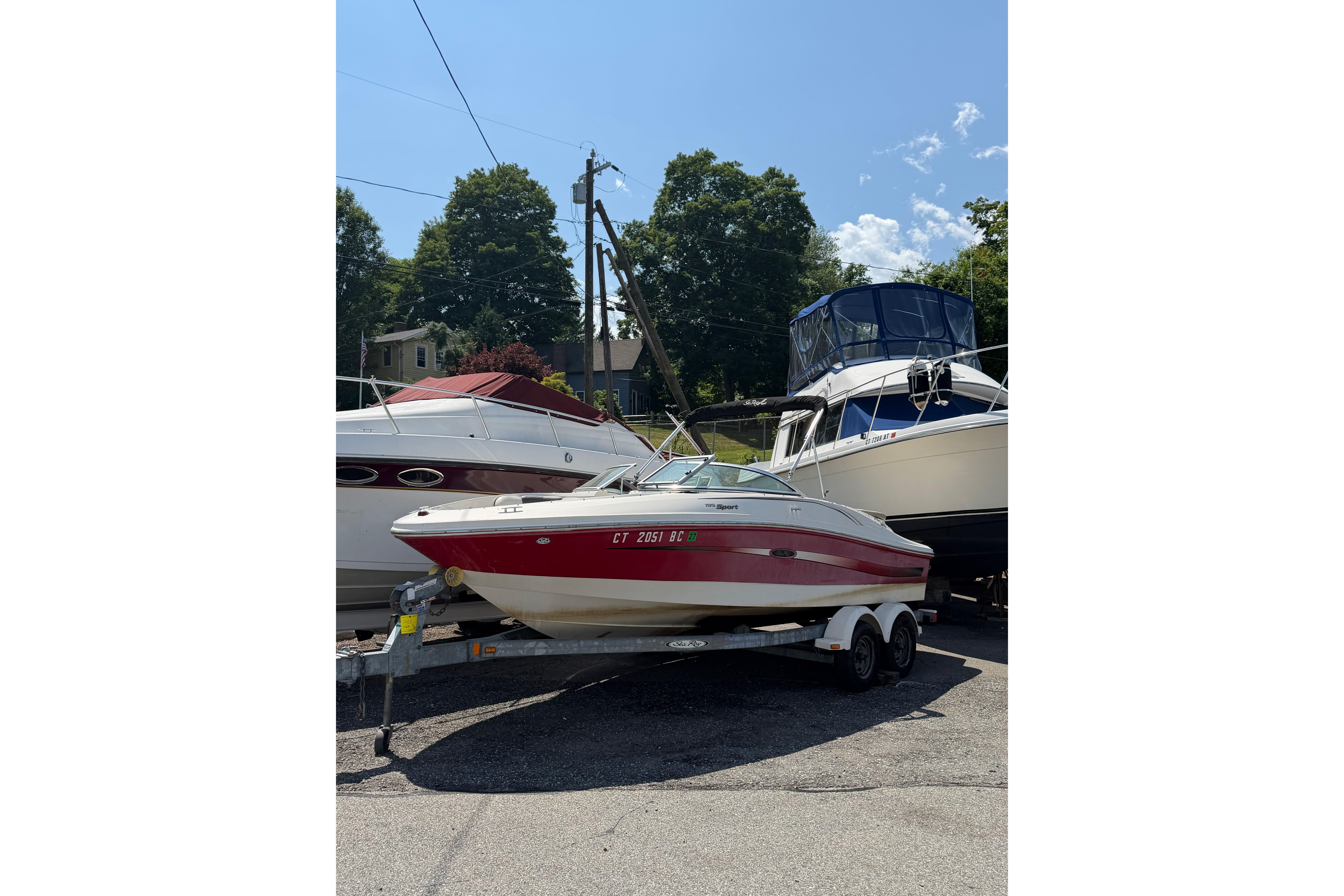 2006 Sea Ray 195 Sport boat on trailer, parked outdoors under clear sky.