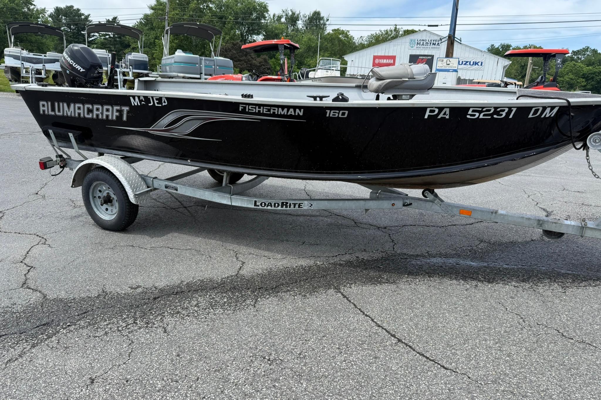 2013 Alumacraft Fisherman 160 Tiller boat on trailer, parked outdoors.