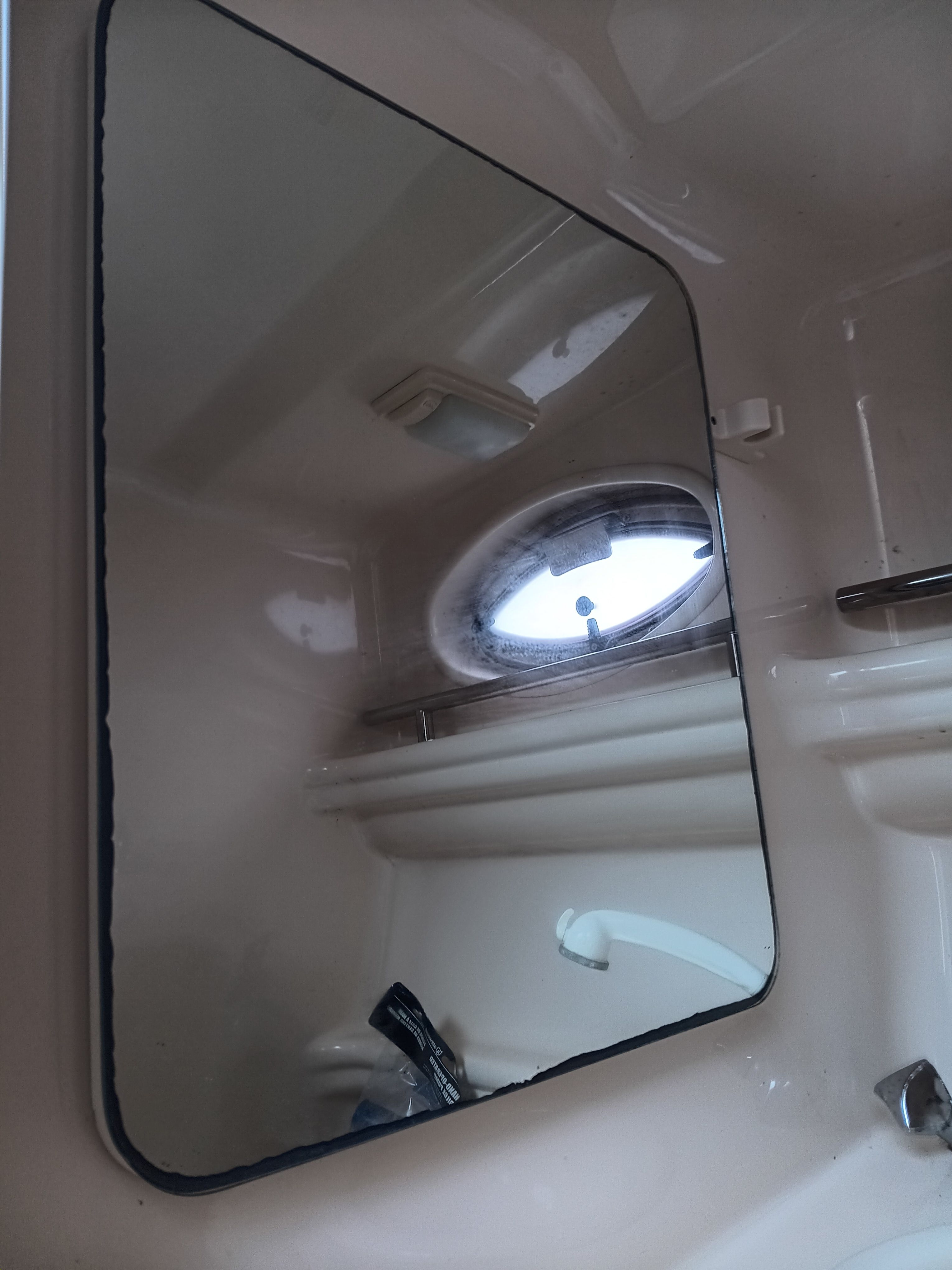 A mirror inside a 2005 Sea Ray 260 DA Sundancer, with a porthole beside it.