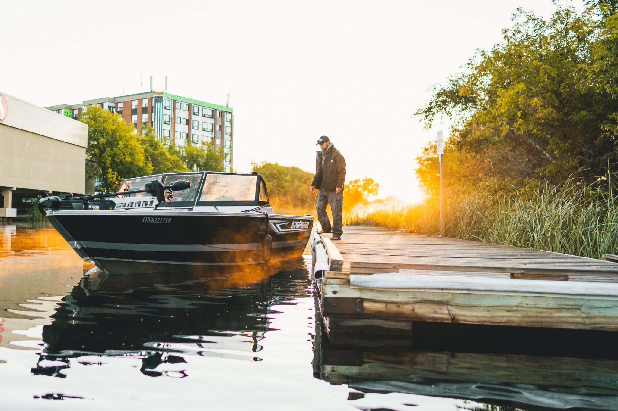 2026 KingFisher 2125 Arrow Sport boat docked at sunset with a person standing nearby.