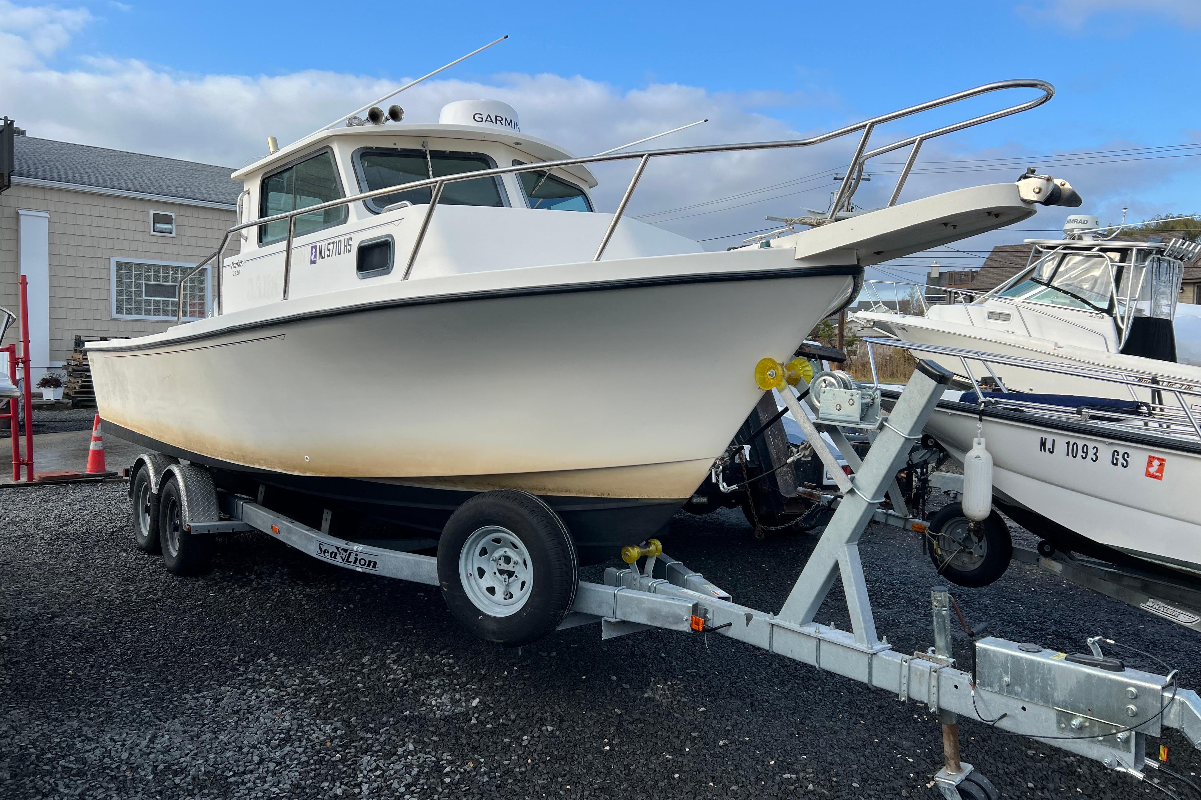 2001 Parker 2520 Deep Vee Sport Cabin boat on trailer, parked outdoors.