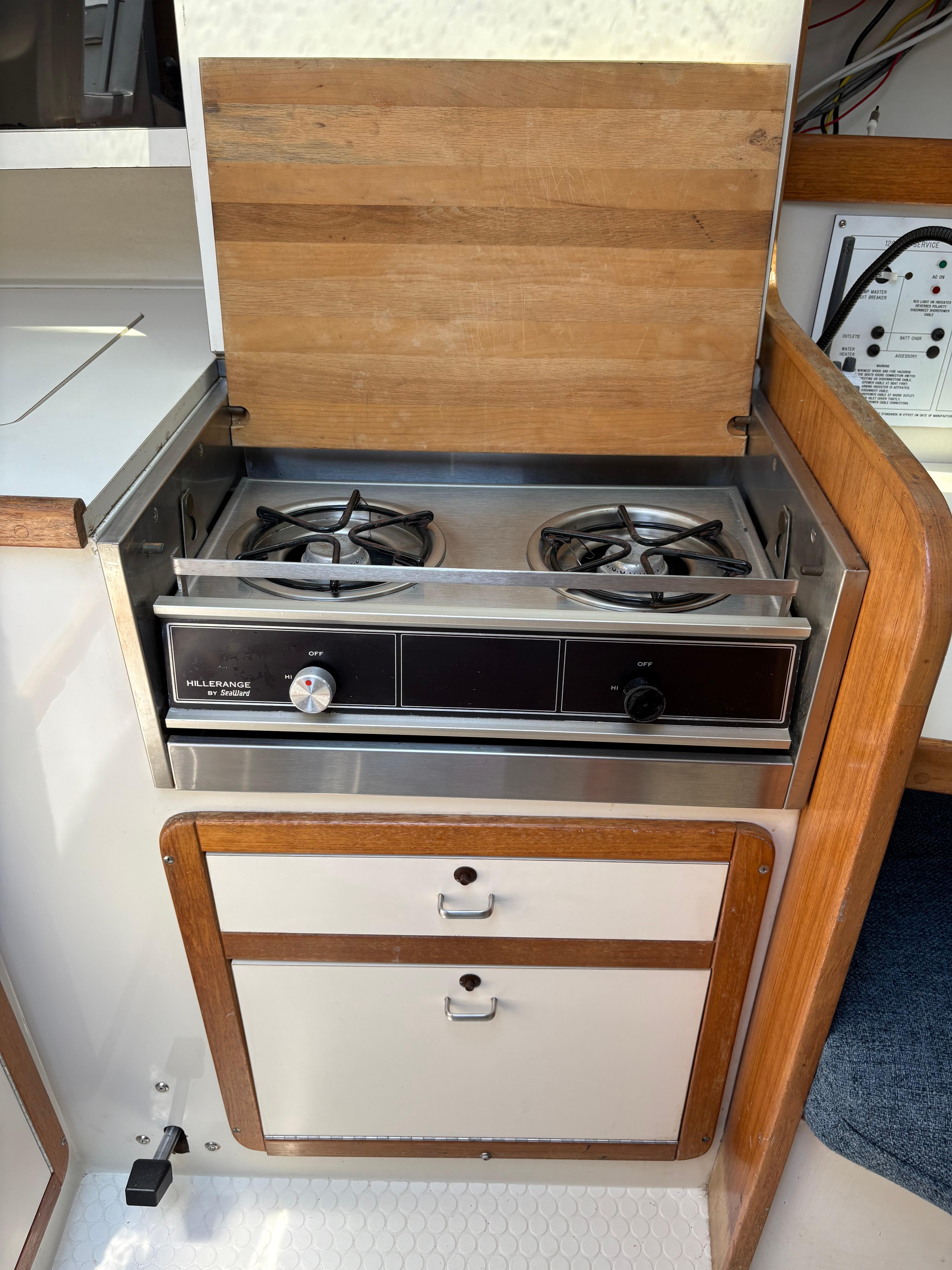 Catalina 270 LE 1994 boat kitchen with two-burner stove and wooden cabinetry.