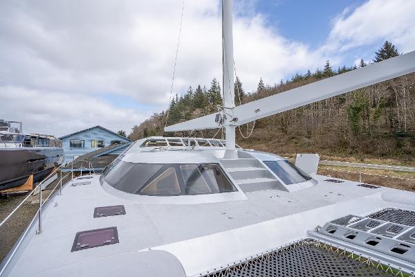 Shuttleworth 52 AeroRig 2025 yacht with sleek design, docked near forested area.