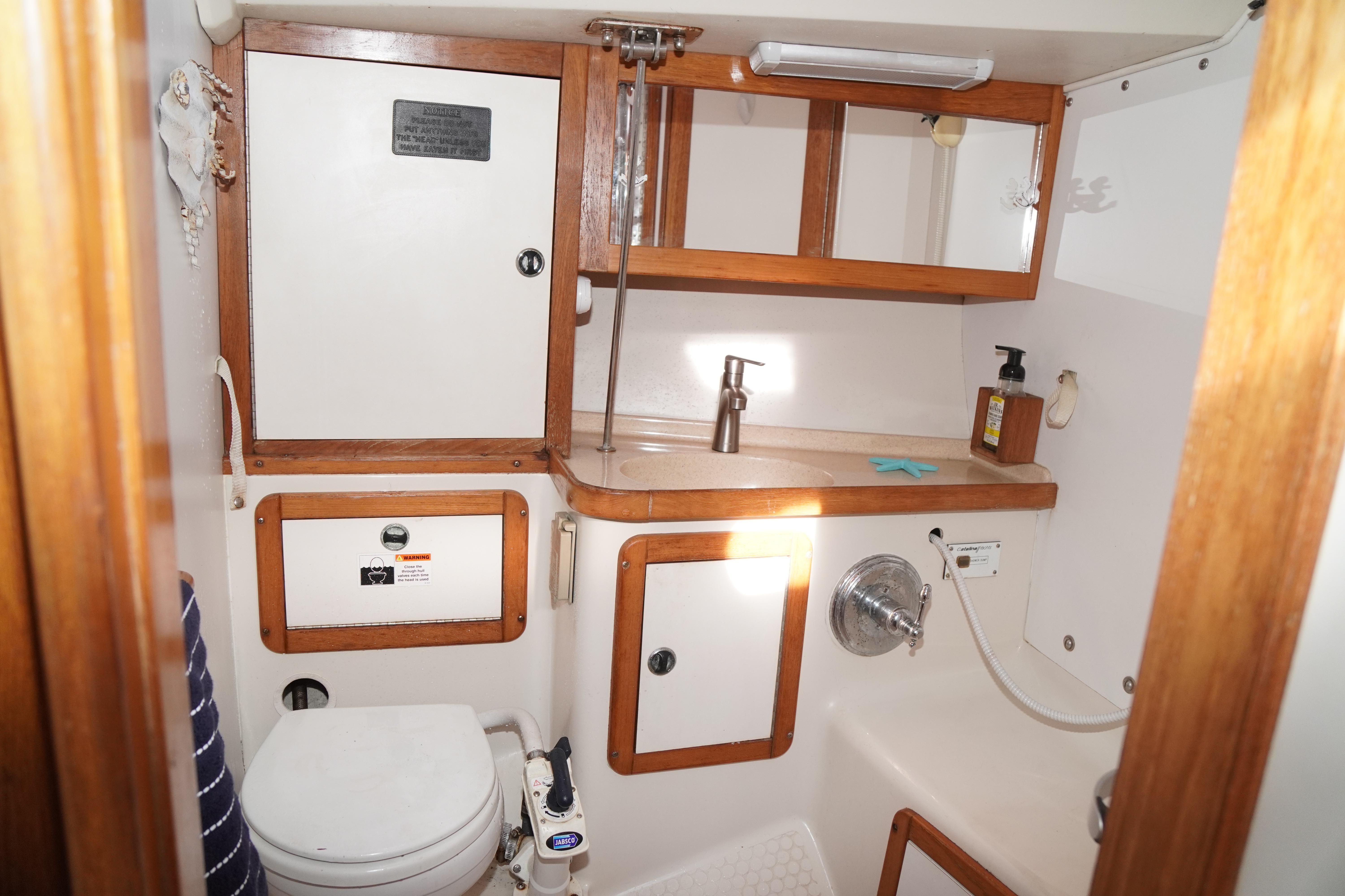 Bathroom interior of 2000 Catalina 36 MkII sailboat with wooden cabinets and fixtures.