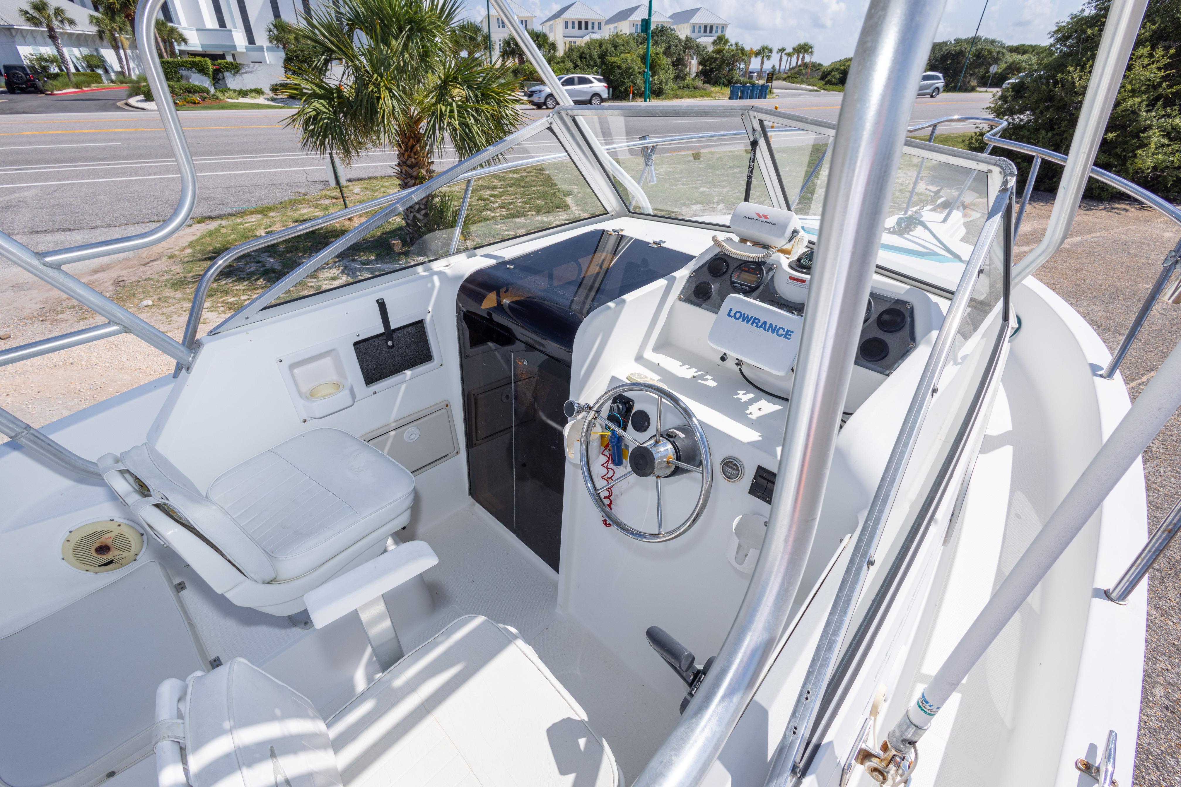 1999 Aquasport 225 Explorer boat cockpit with steering wheel and navigation equipment.
