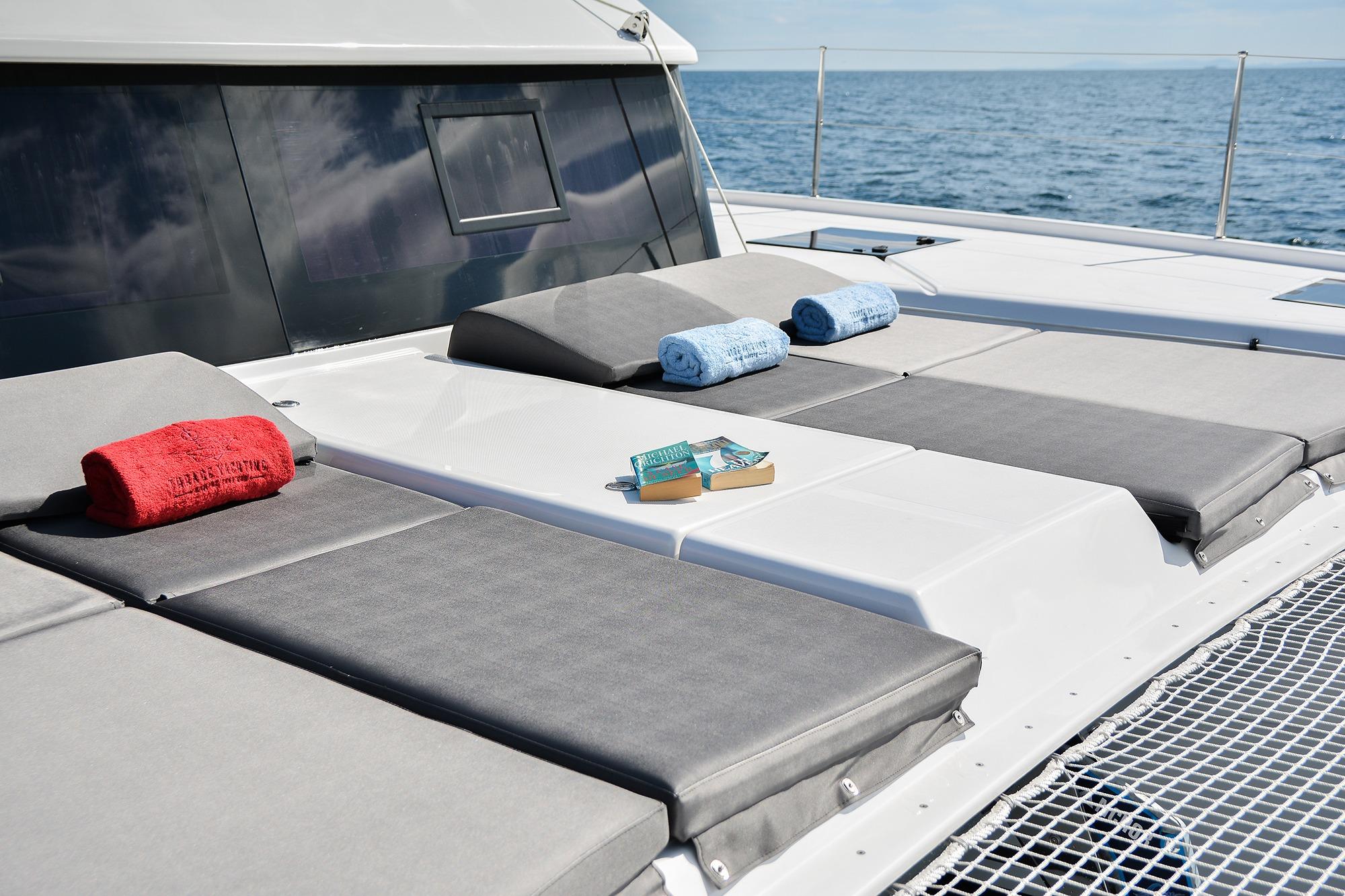 Luxurious sunbathing area on 2020 Dufour Catamarans 48, featuring towels and a book.
