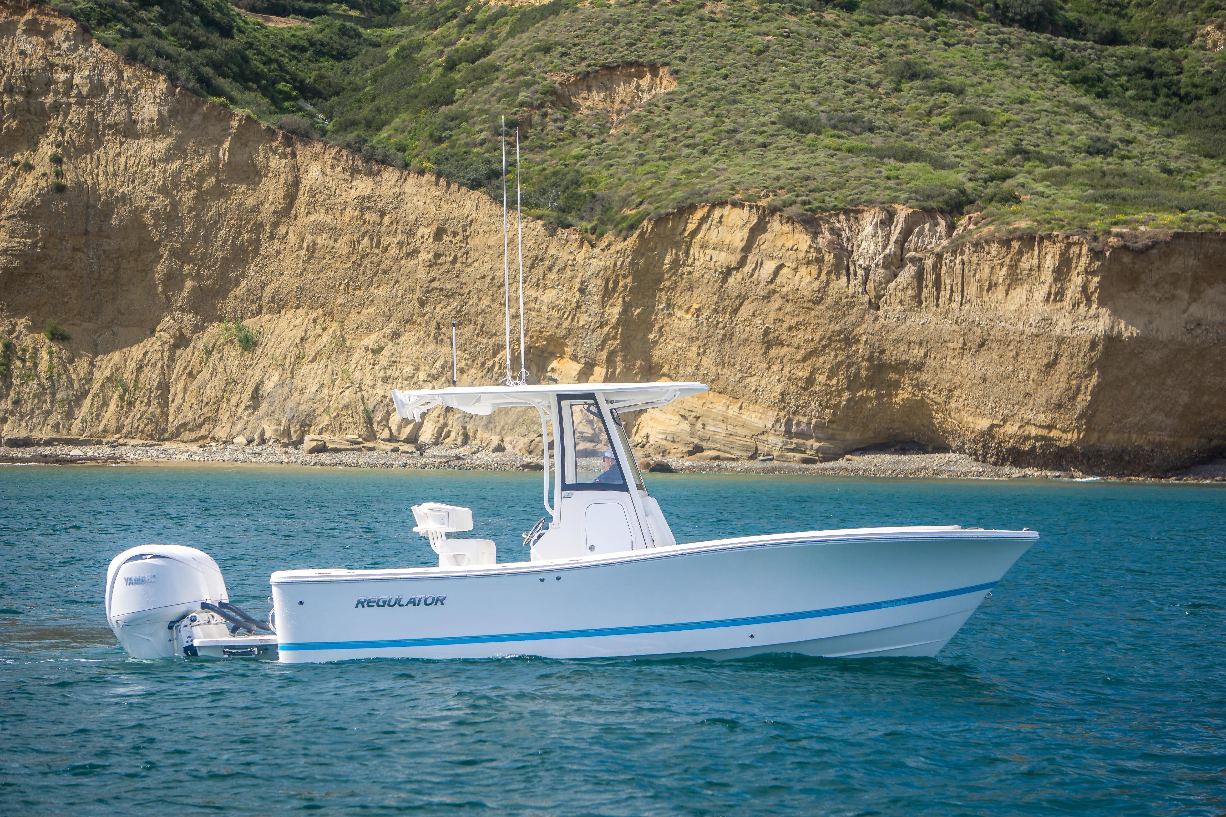 2026 Regulator 23 boat cruising near rocky coastline.